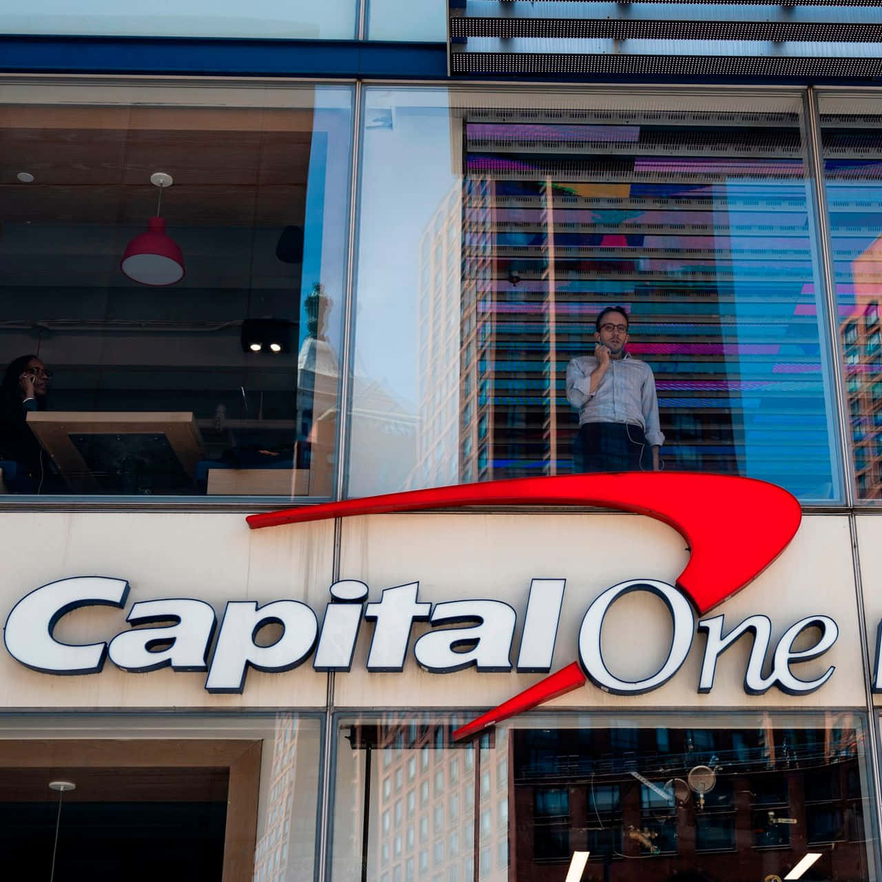 Capital One辦公室窗戶，男子站在裡面反射建築物
