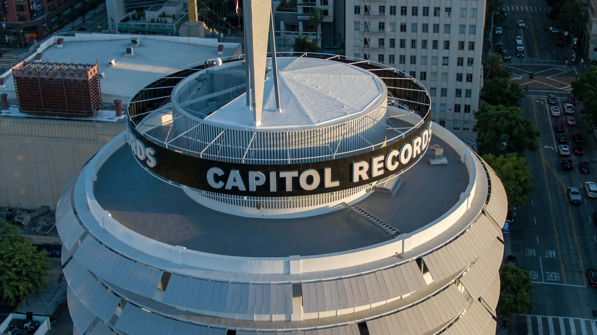 Capitol Records大樓的壯觀航拍圖 壁紙 — 從空中俯瞰標誌性的 Capitol Records 大樓，其圓形設計和「CAPITOL RECORDS」標誌在金色陽光下閃耀。