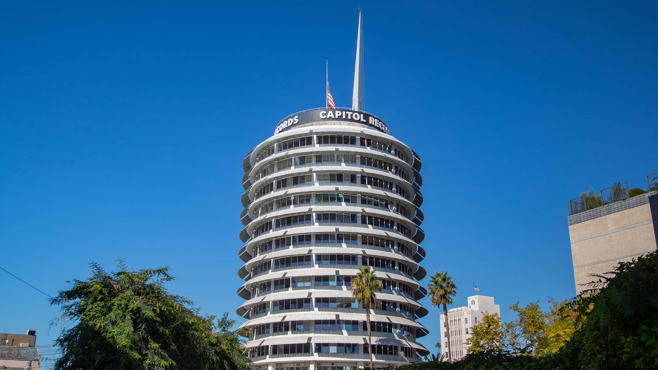 Capitol Records大樓的絕美視角 壁紙 — 一座引人注目的白色圓柱形Capitol Records大樓在晴朗的藍天下聳立，底部有棕櫚樹。