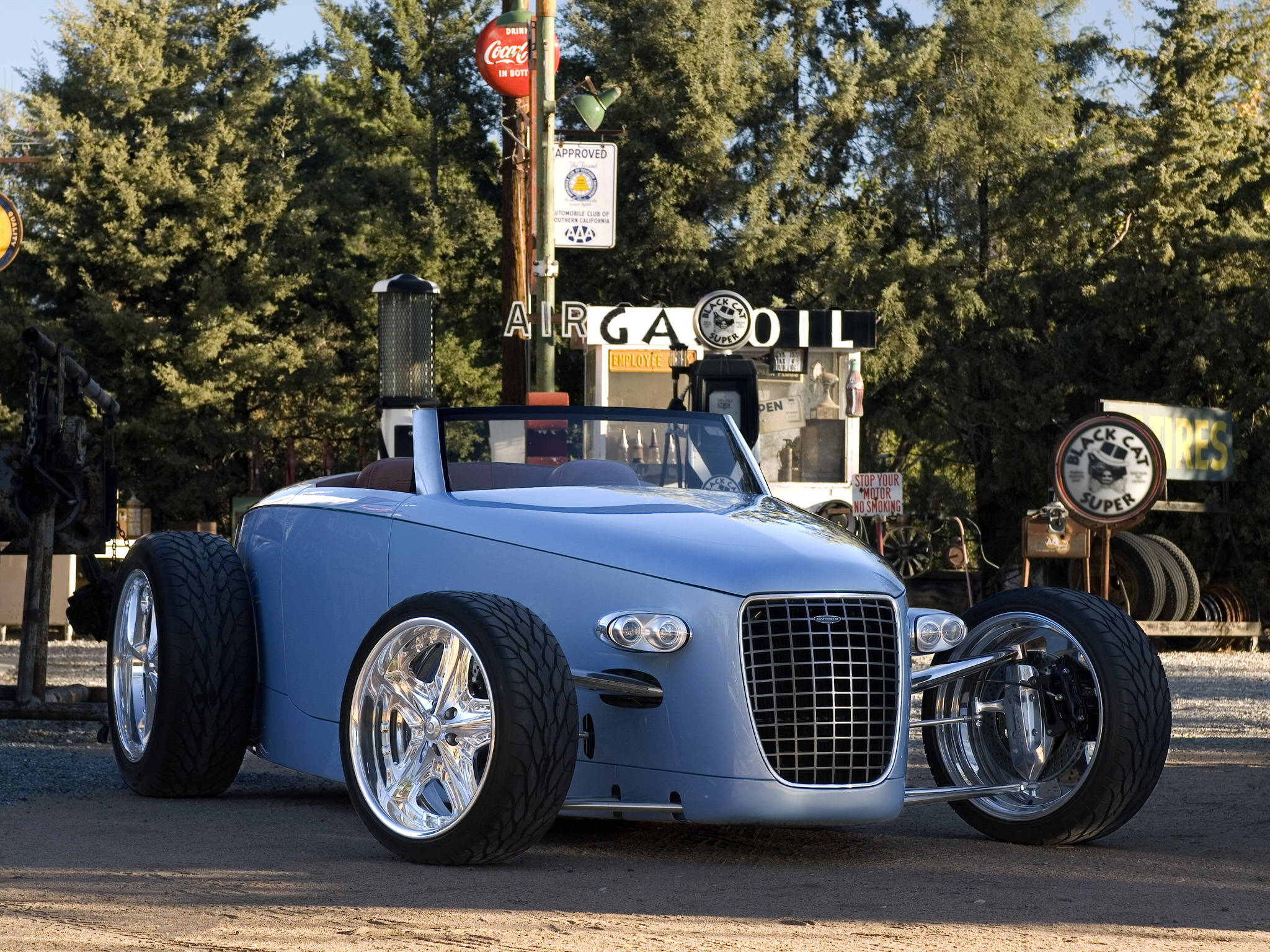 Caresto V8 Volvo iPhone 壁紙 — 一架時尚嘅淺藍色定制熱棒，配備鉻合金輪圈同背景中嘅復古加油站標誌。