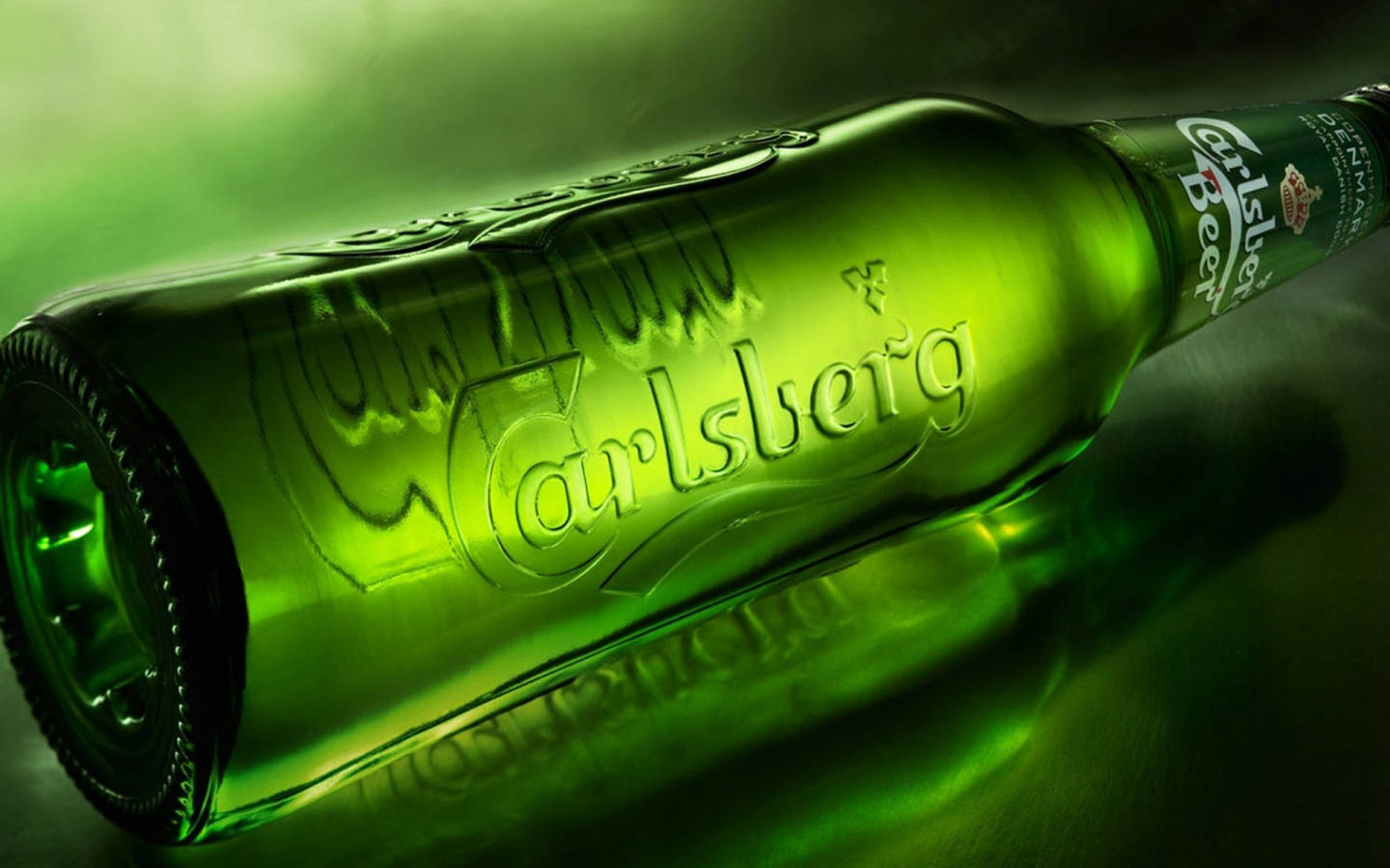 Carlsberg啤酒飲品單瓶 壁紙 — 一支有光澤的綠色嘉士伯啤酒瓶以對角線放置在反光表面上，在戲劇性的綠色燈光下。