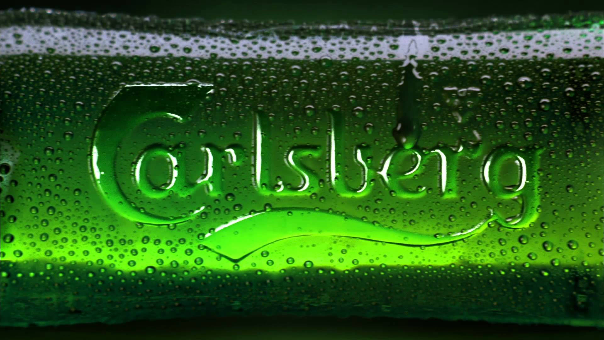 Carlsberg啤酒飲品標誌 壁紙 — 冰凍綠色嘉士伯啤酒瓶的特寫，瓶身佈滿冷凝水滴，在霓虹燈下閃閃發光。