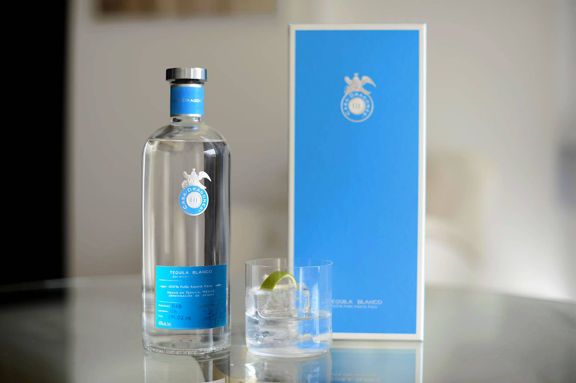 龍舌蘭酒瓶和加冰及青檸的玻璃杯在反射表面上。