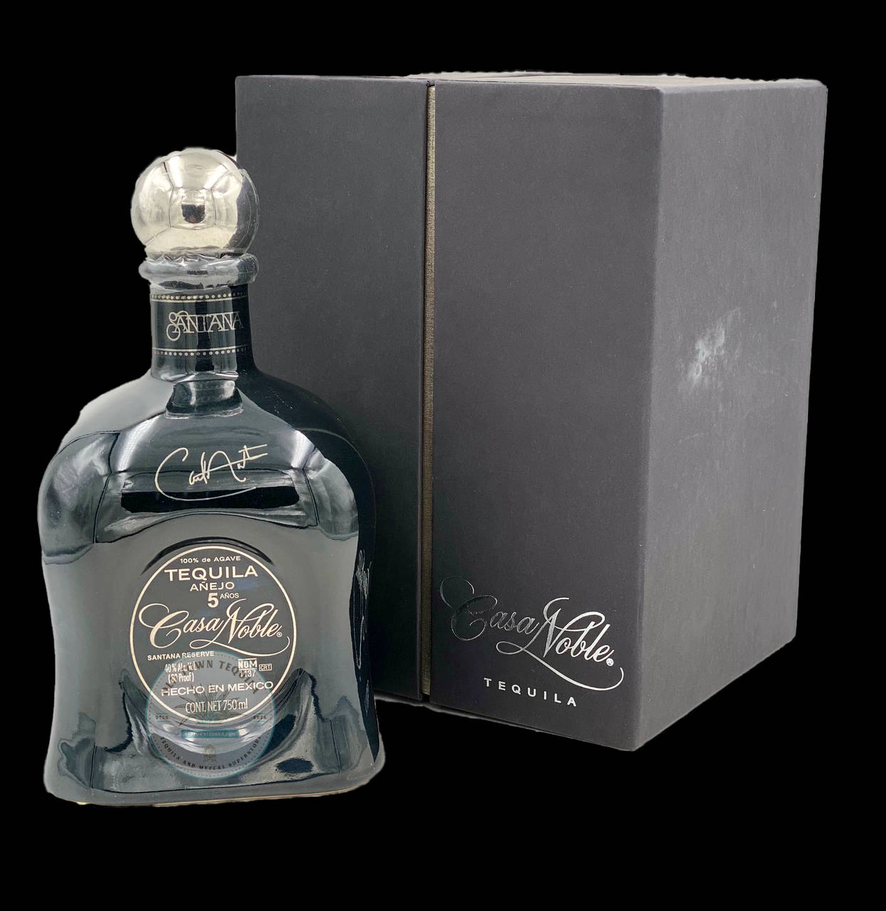 Casa Noble 龍舌蘭酒 Extra 壁紙 — 一個時尚的深藍色Casa Noble龍舌蘭酒瓶配銀色瓶蓋，旁邊放著它的啞光黑色盒子，背景是純黑色。