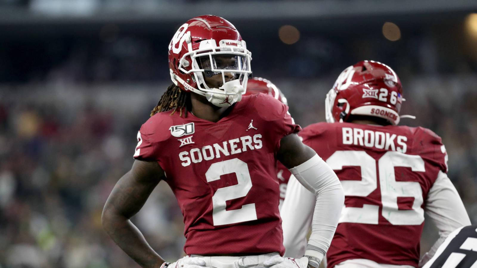 Ceedee Lamb 與 Kennedy Brooks 壁紙 — 兩名身穿紅色球衣的奧克拉荷馬大學 Sooners 美式足球員在球場燈光下，於比賽期間站在場上。