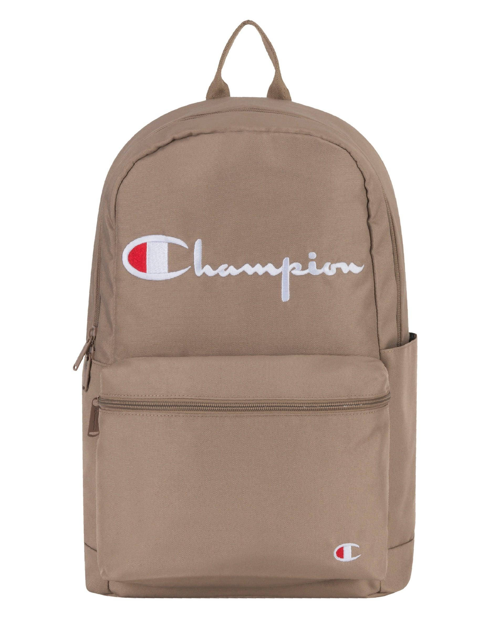 Champion 米色背包 壁紙 — Tan Champion 背囊，帶有白色草書標誌和紅色徽章，背景為純白色。