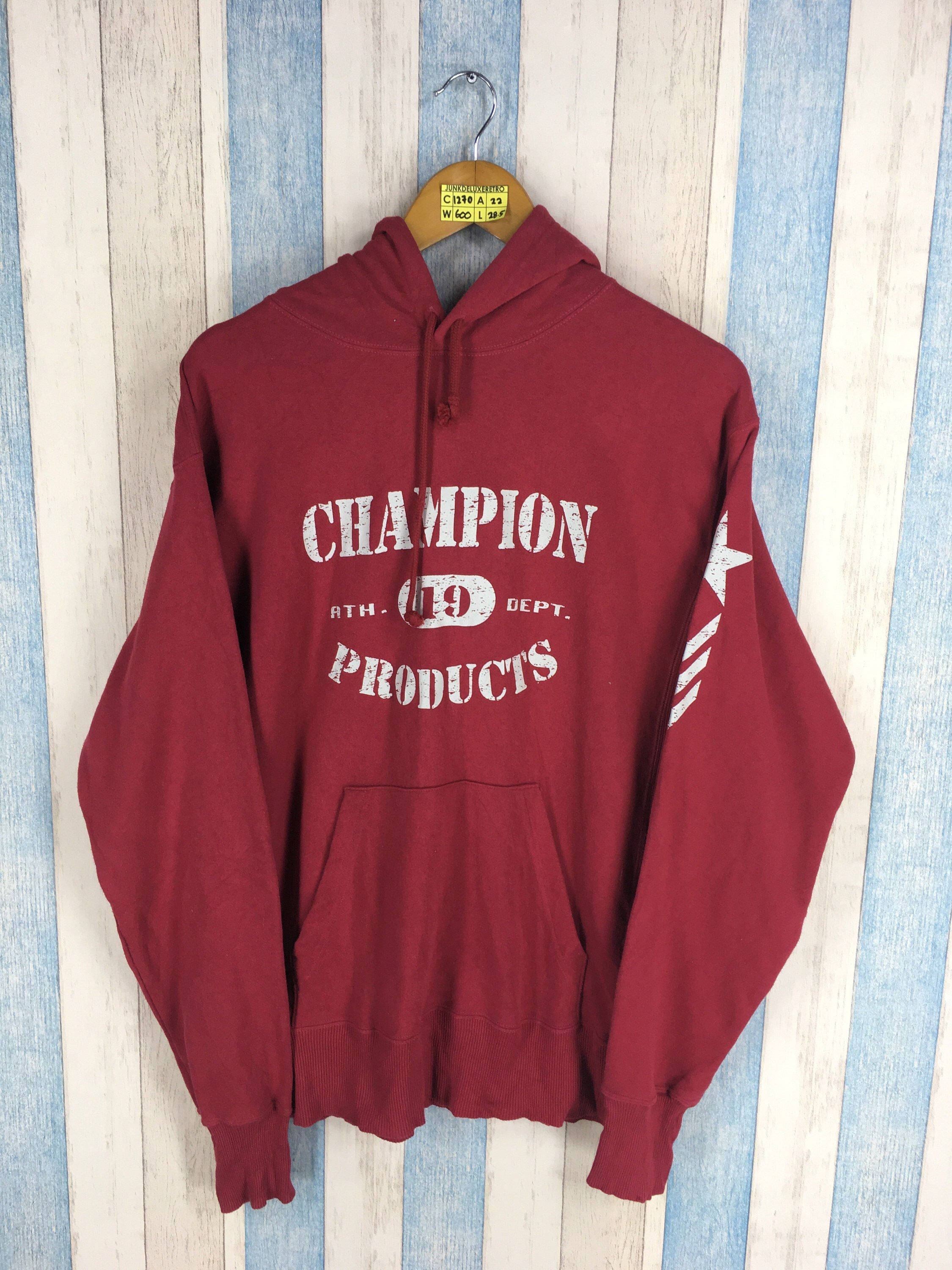 Champion 紅色磨損夾克 壁紙 — 一件復古酒紅色Champion連帽衫，帶白色標誌，掛在木衣架上，背景是藍白條紋木牆。