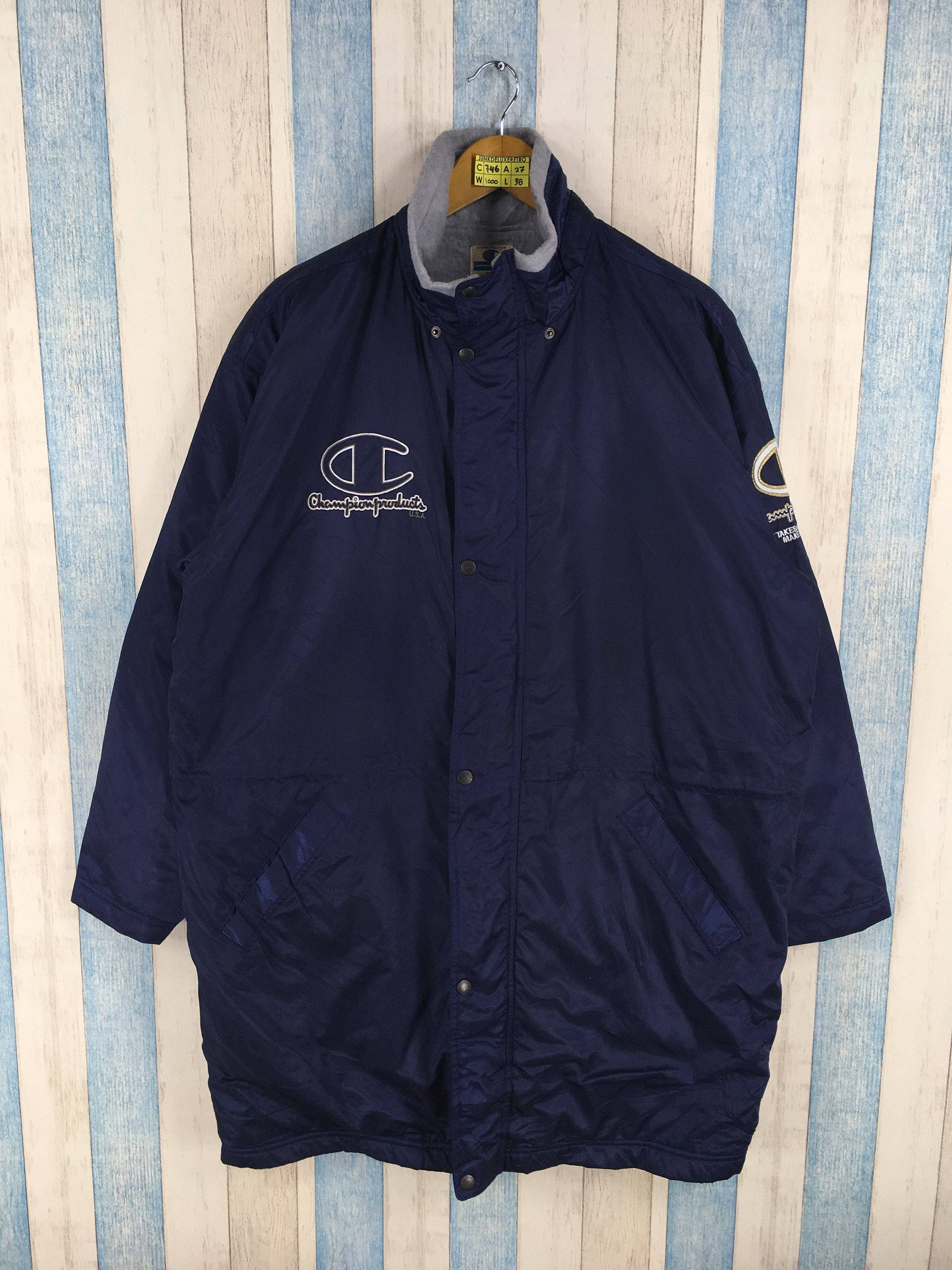 Champion 藍色風衣：潮流與實用兼具 壁紙 — 一件海軍藍色的Champion防風外套掛在衣架上，背景是藍白條紋的木牆。