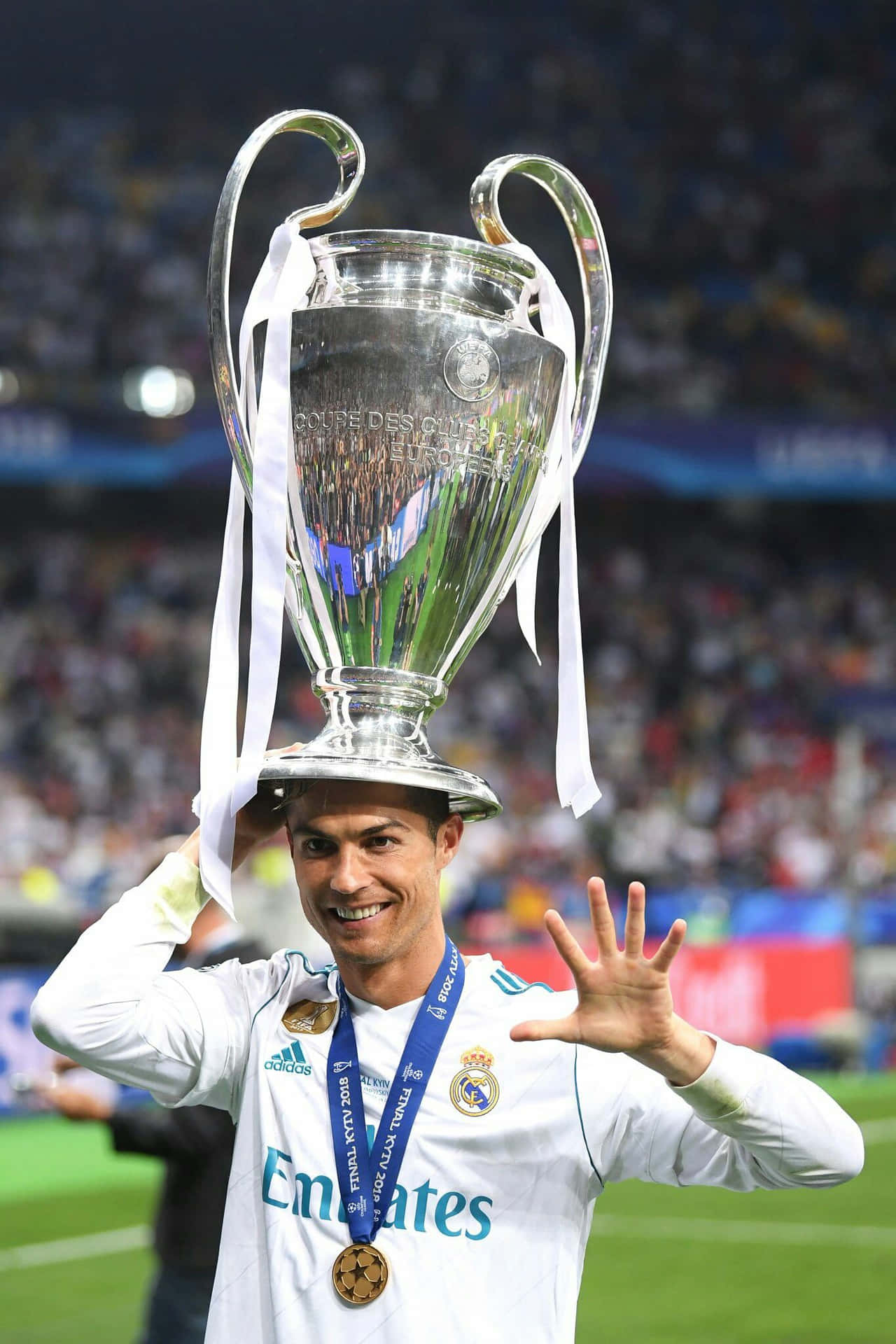 足球員將 UEFA 歐聯獎盃放在頭上並向人群揮手。