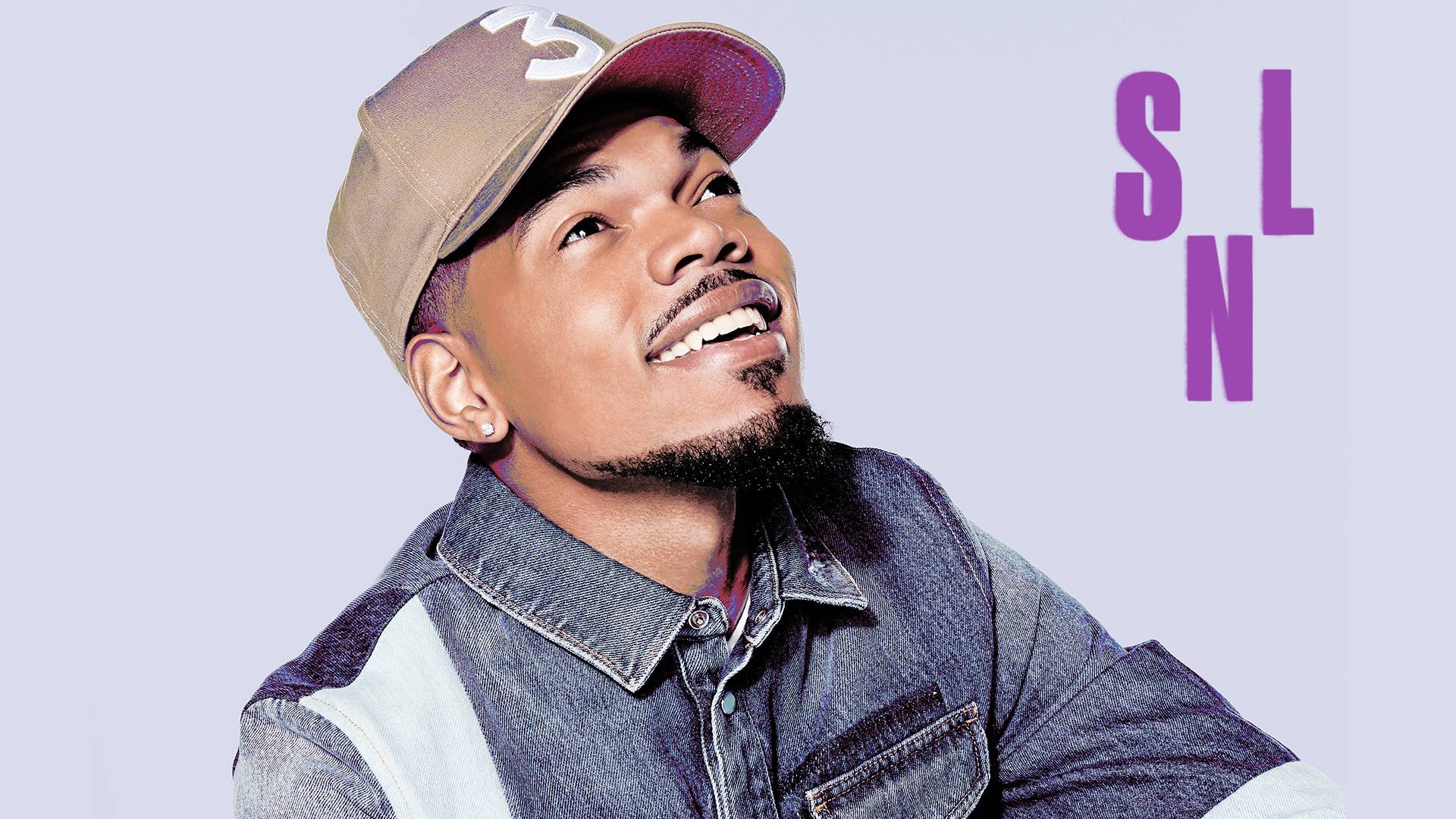 Chance The Rapper 登上 SNL 壁紙 — 一位微笑的男子身穿牛仔外套和帽子，在柔和的薰衣草背景上仰望粗體紫色字母。