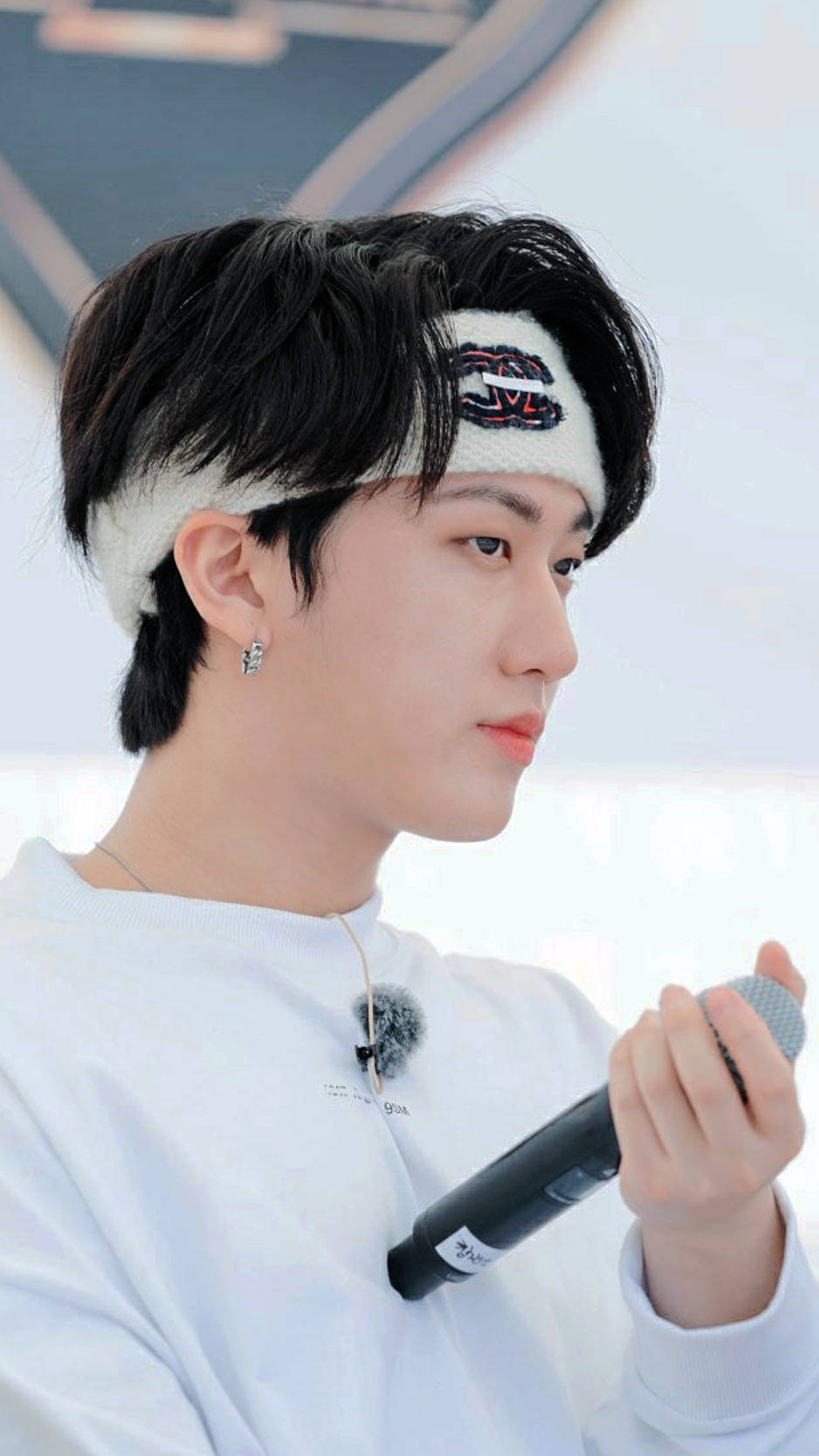 Changbin 排練照 壁紙 — 一位深色頭髮、戴白色頭帶的年輕男子，在明亮的環境中手持麥克風，視線望向一旁。