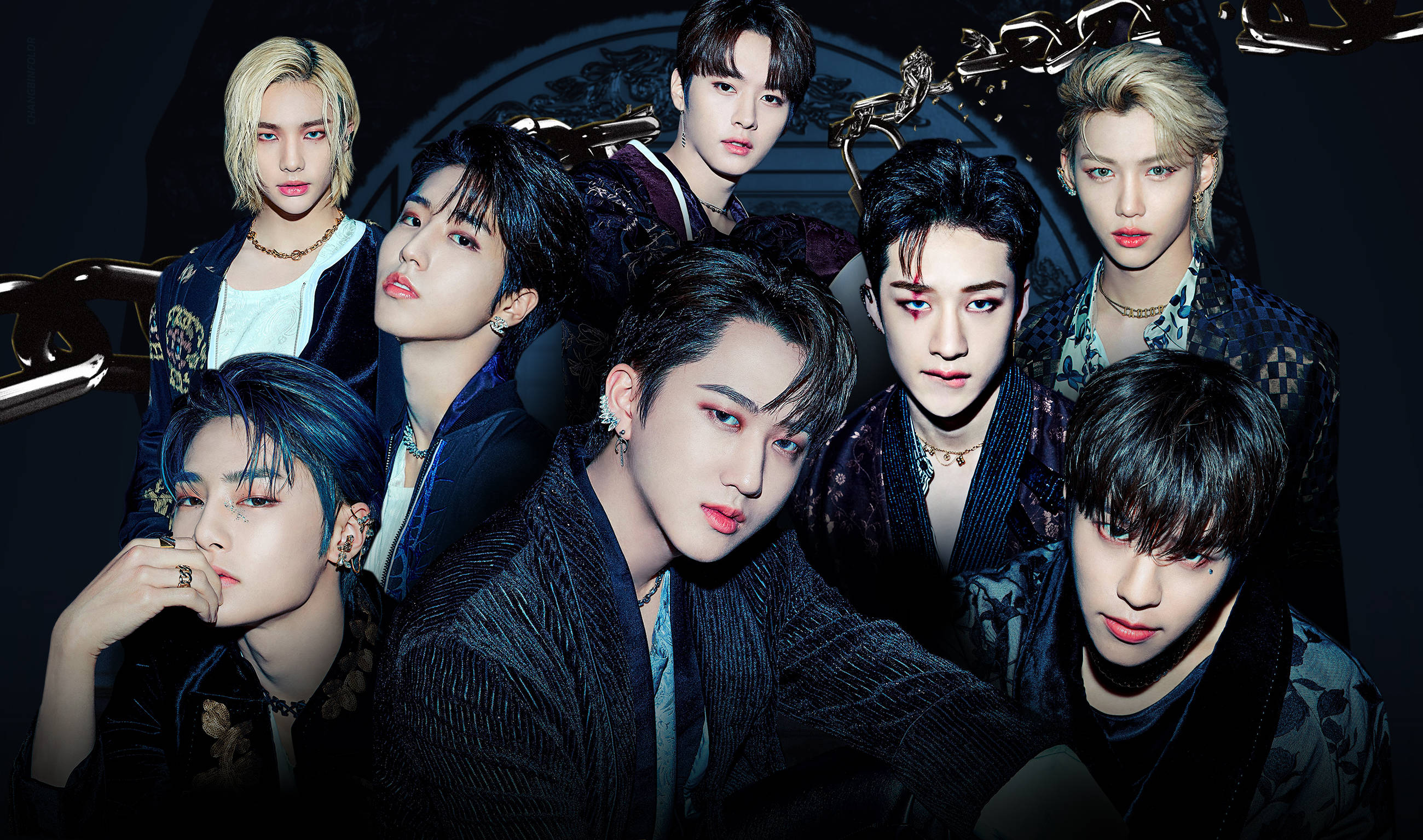 Changbin 男子團體成員 壁紙 — 七位時尚年輕男子，妝容大膽，身穿深色服裝，在充滿氛圍的燈光下，於鏈條環形背景前戲劇性地擺姿勢。