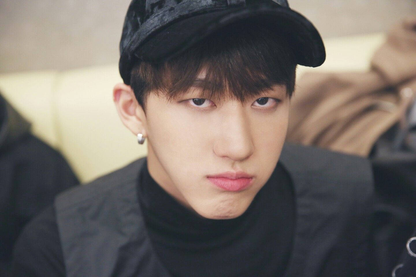 Changbin 的撒嬌照 壁紙 — 一名戴黑色鴨舌帽和高領毛衣的年輕男子，表情嚴肅地凝視著相機。
