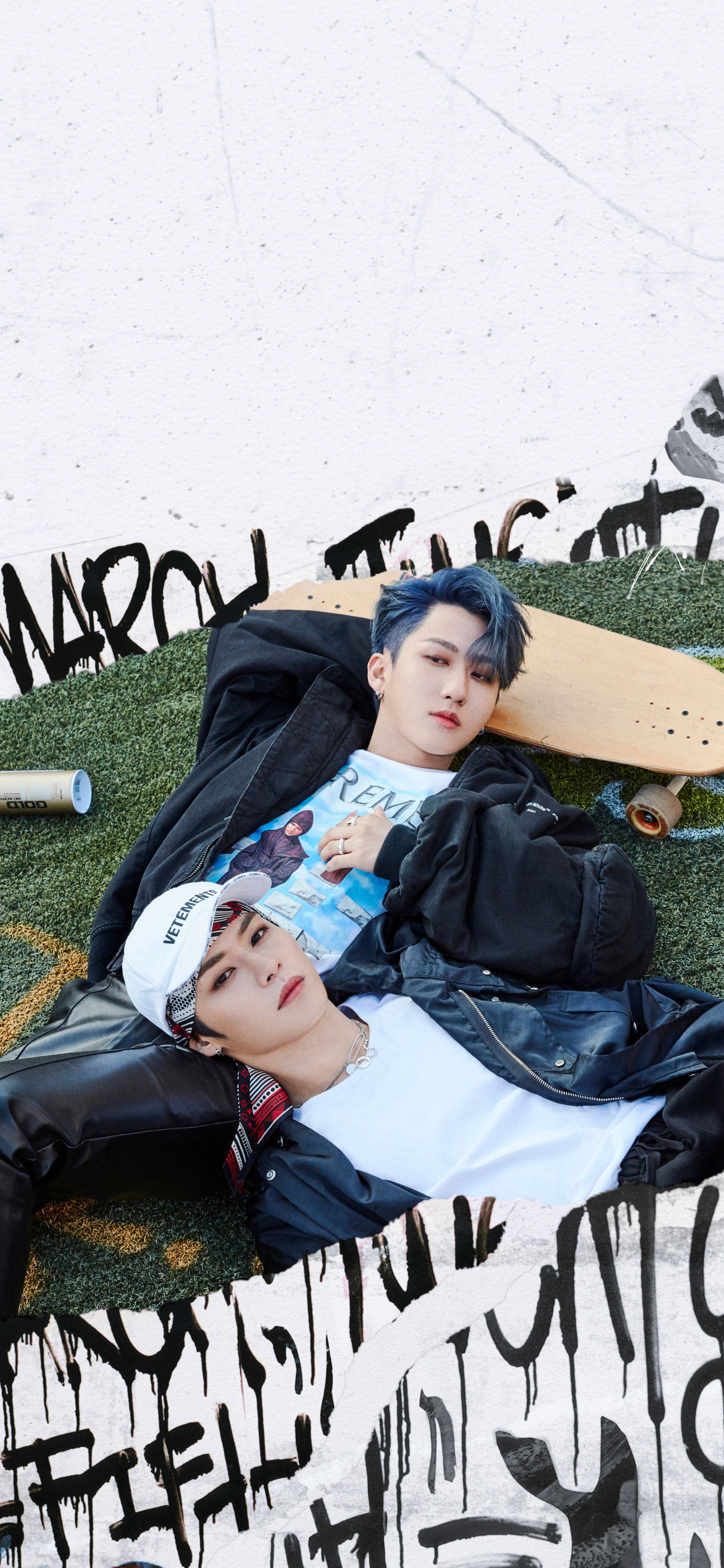 Changbin 與 Lee Know 壁紙 — 兩名藍髮年輕男子躺在滑板旁邊的草地上，上方是佈滿塗鴉的牆壁。