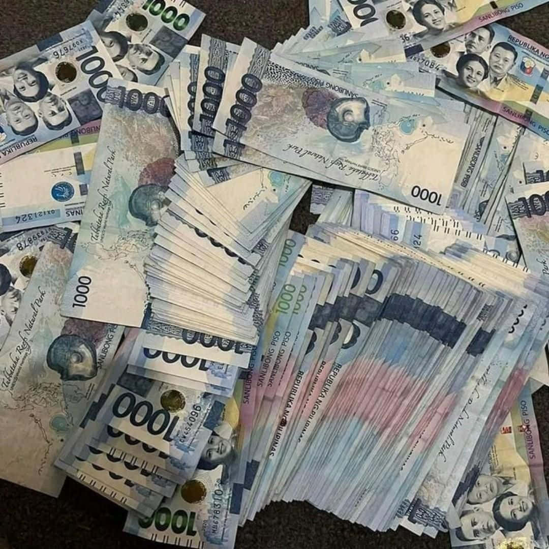  壁紙 — 一疊混亂的菲律賓1000披索鈔票在深色地毯上扇形散開，展示肖像和國家地標。
