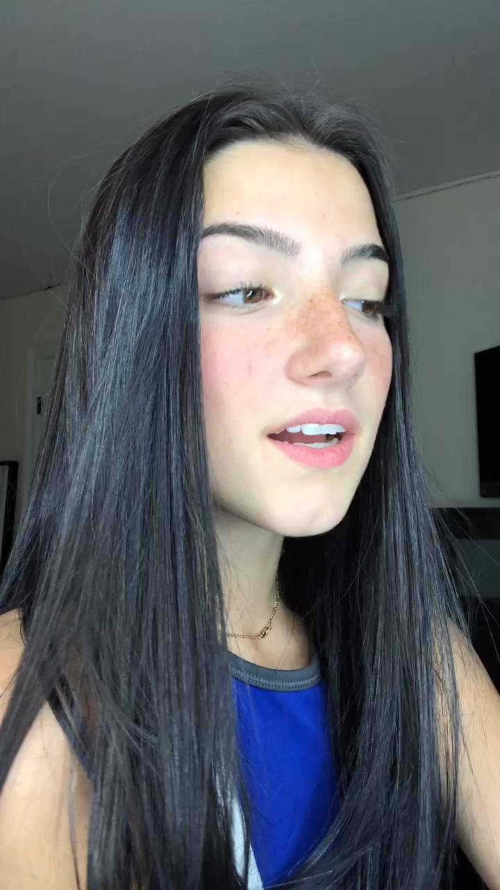 Charli Damelio 藍色造型 壁紙 — 一位長黑髮、有雀斑的年輕女性在休閒的室內環境中看向鏡頭外。