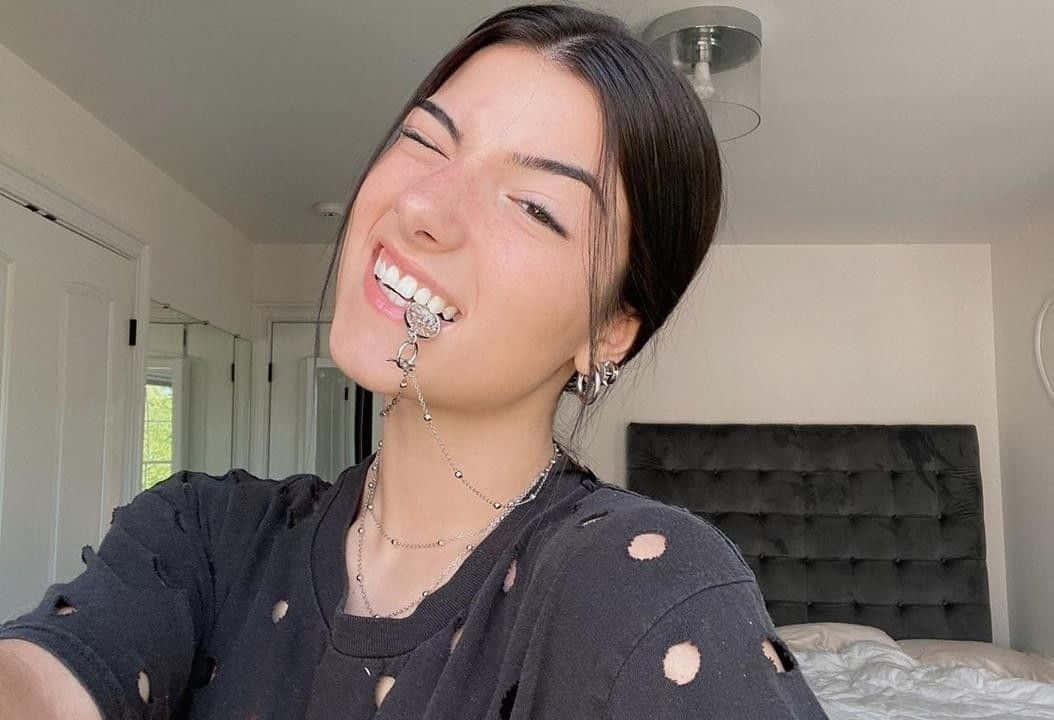 年輕女性在臥室穿著破爛黑色襯衫和銀飾大笑