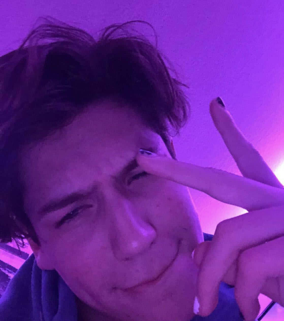 在紫色燈光下眨眼並指向眼睛的人