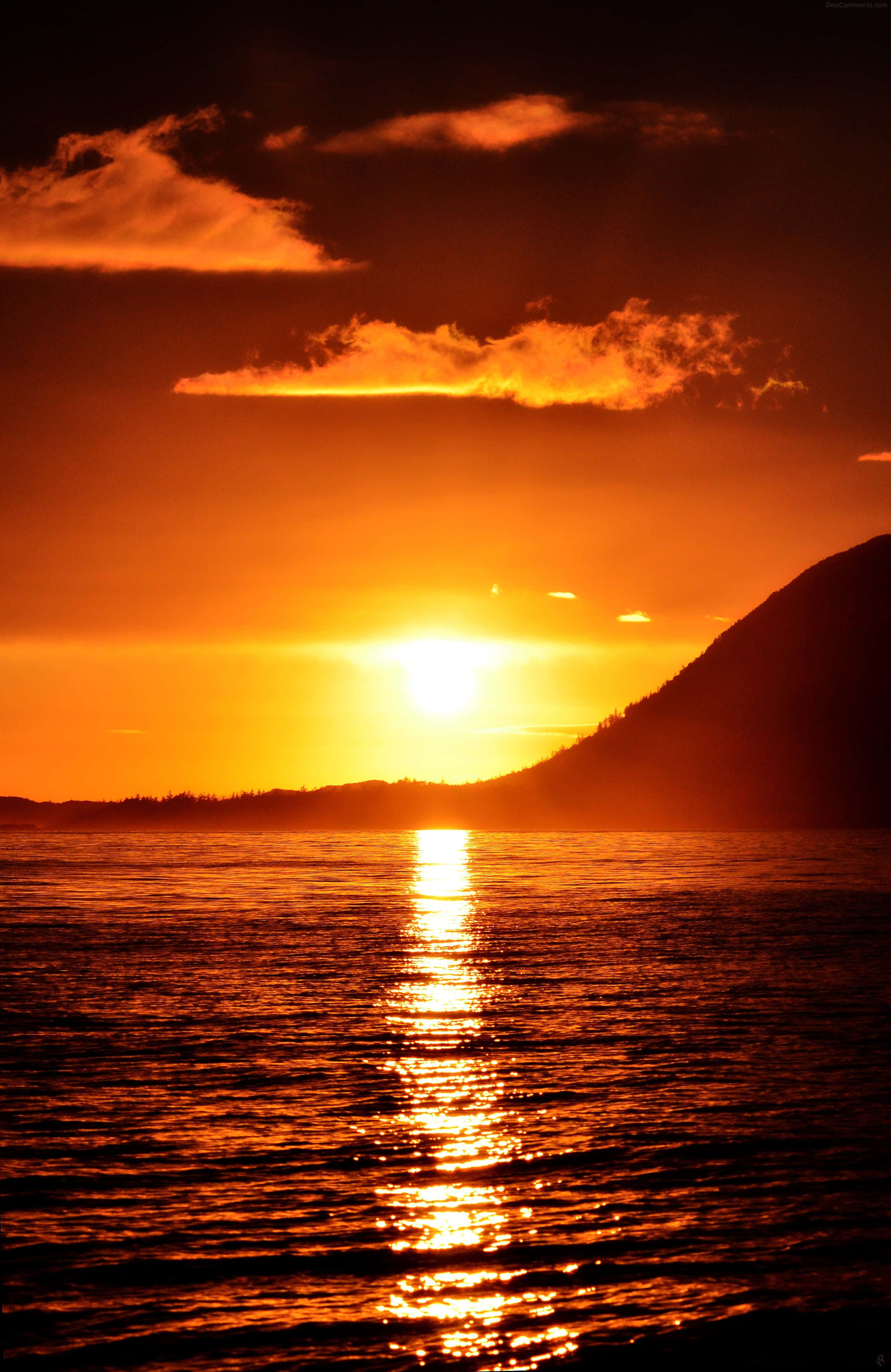 Sunset View 桌布 壁紙 — 熾熱的夕陽將天空和水面染成鮮豔的橙色，太陽在輪廓山後方落下。