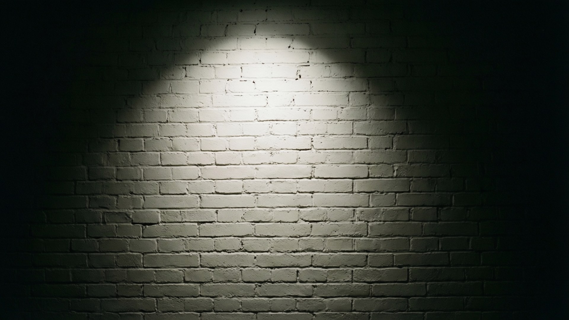 Chiaroscuro Brick 壁紙 — 一盞聚光燈照亮白色磚牆，在其邊緣投射出深色陰影。