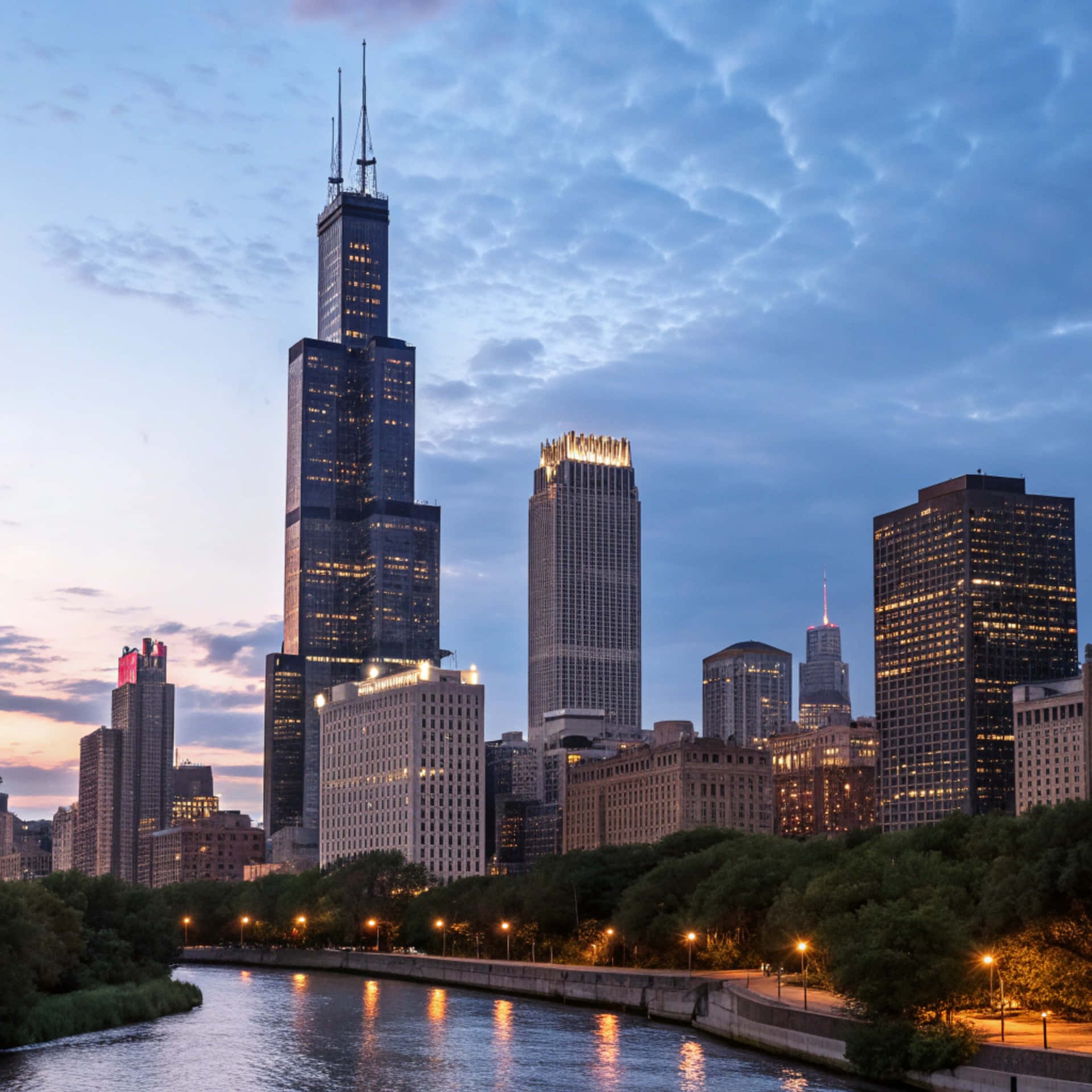 Chicago Skyline 壁紙 — 芝加哥天際線在黃昏時分，威利斯塔在紋理藍天的映襯下亮起，倒映在下面的河流中。
