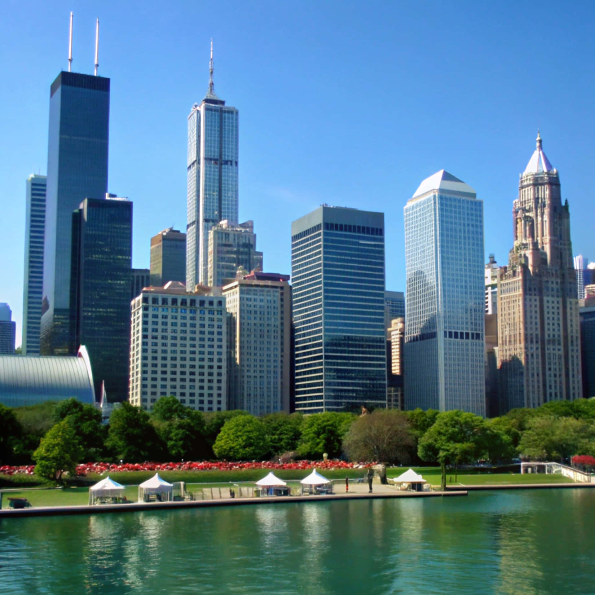 Chicago Skyline 壁紙 — 芝加哥天際線，玻璃摩天大樓，綠色公園，白色帳篷，平靜湖泊，清澈藍天。