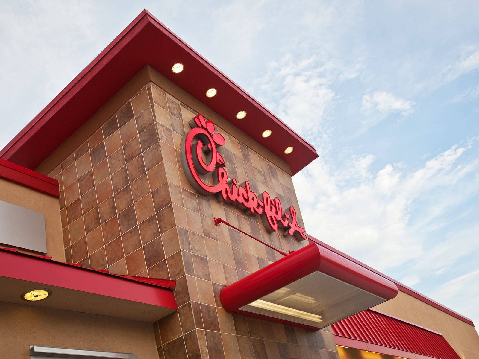 Chick Fil A 標誌招牌 壁紙 — 從低角度觀看Chick-fil-A餐廳，紅色飾邊和標誌襯托著部分多雲的藍天。