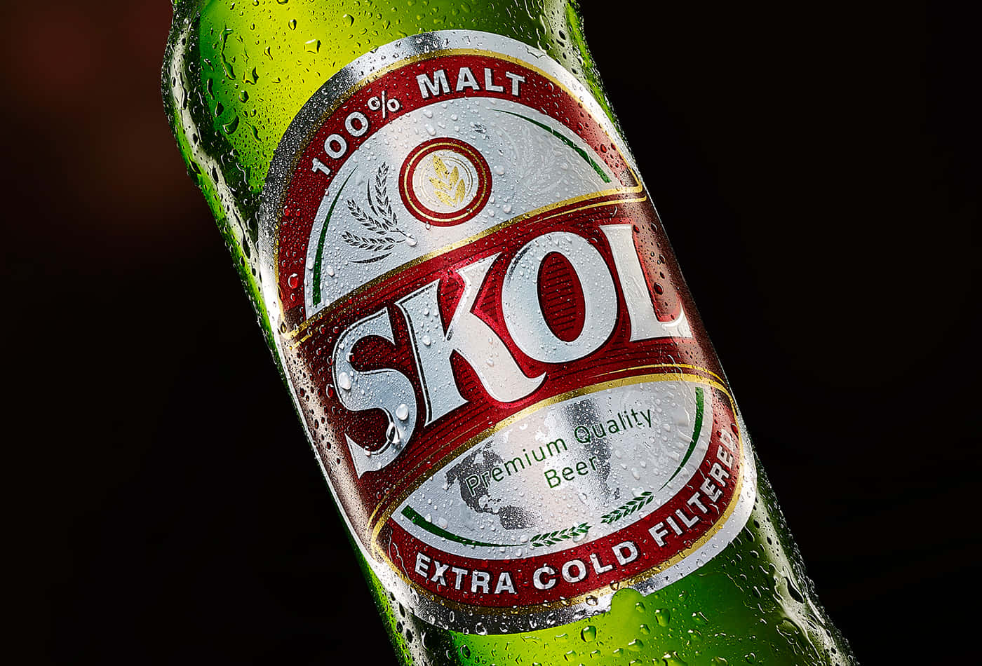  壁紙 — 冰凍的綠色Skol啤酒瓶在深色背景下閃爍著冷凝水珠。
