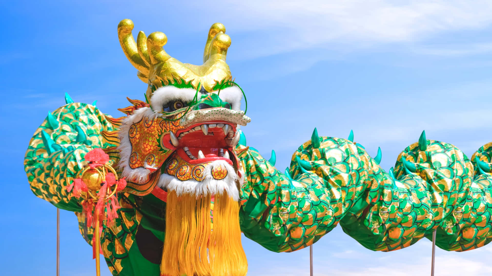  壁紙 — 一件充滿活力的綠色和金色舞龍服裝，帶有兇猛的面孔和飄逸的鬍鬚，映襯著清澈的藍天。