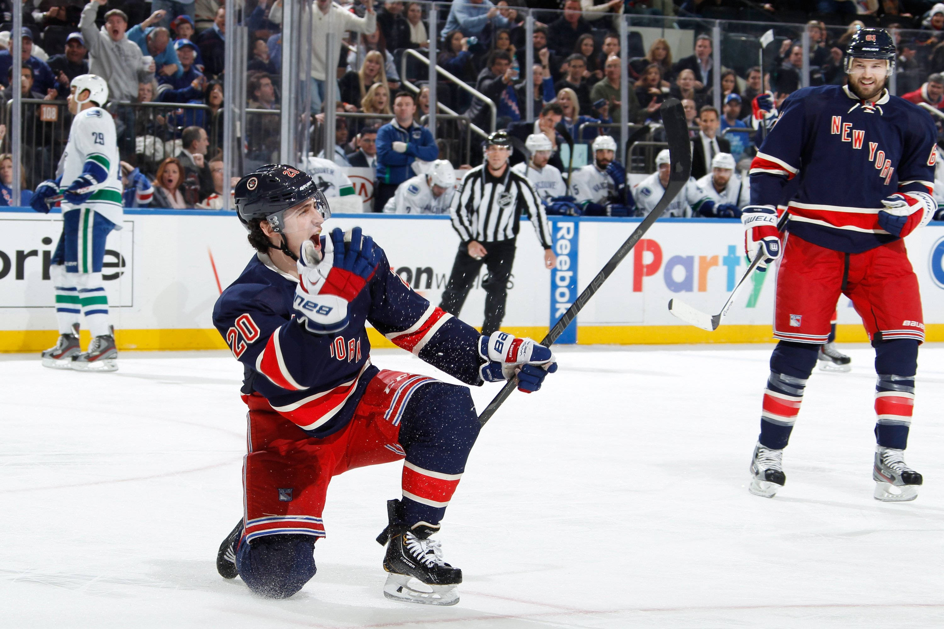 Chris Kreider 與 Cam Talbot 紐約遊騎兵隊 壁紙 — 身穿藍紅球衣的冰球運動員跪在冰上，高舉球棍慶祝，觀眾在玻璃後歡呼。