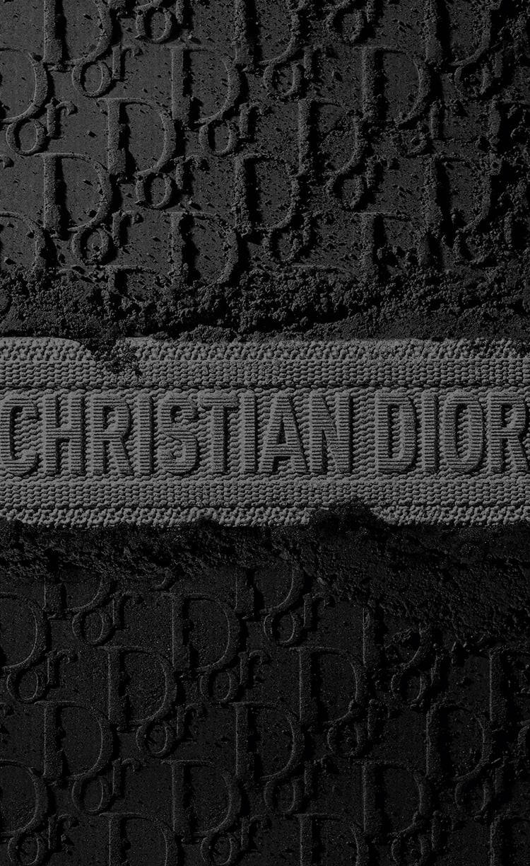 壓花 Christian Dior 標誌圖案在紋理黑色布料上的特寫。