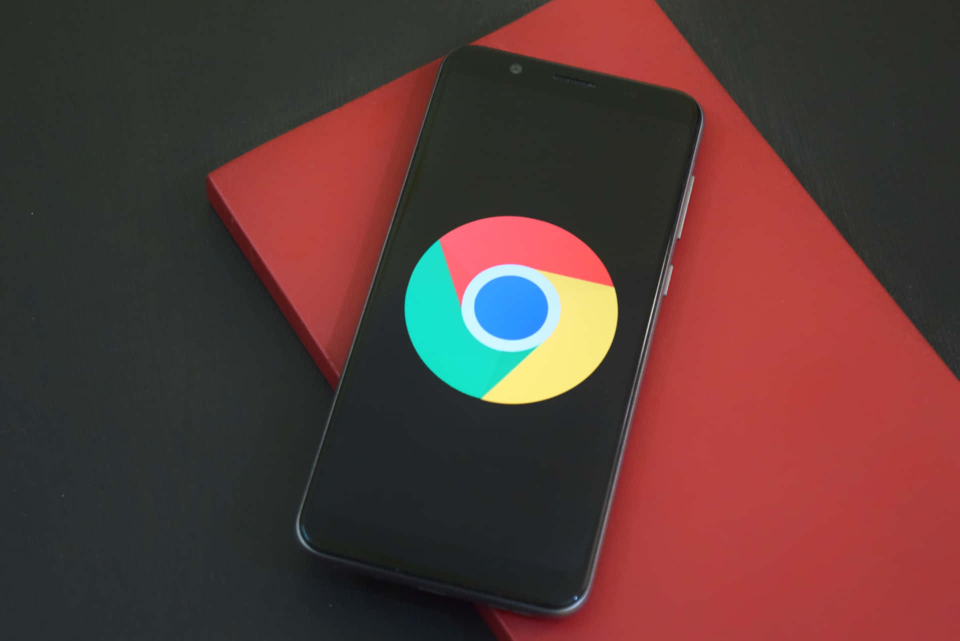 智能手機在紅色筆記本上顯示Chrome標誌