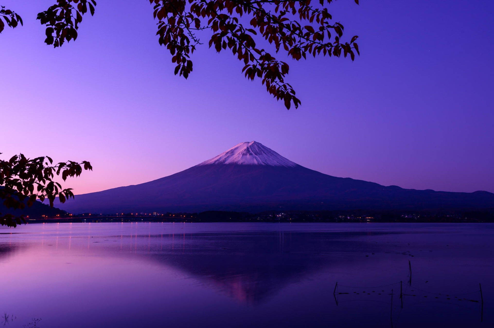 暮色中的富士山倒映在寧靜的湖面上，秋葉環繞著景色。
