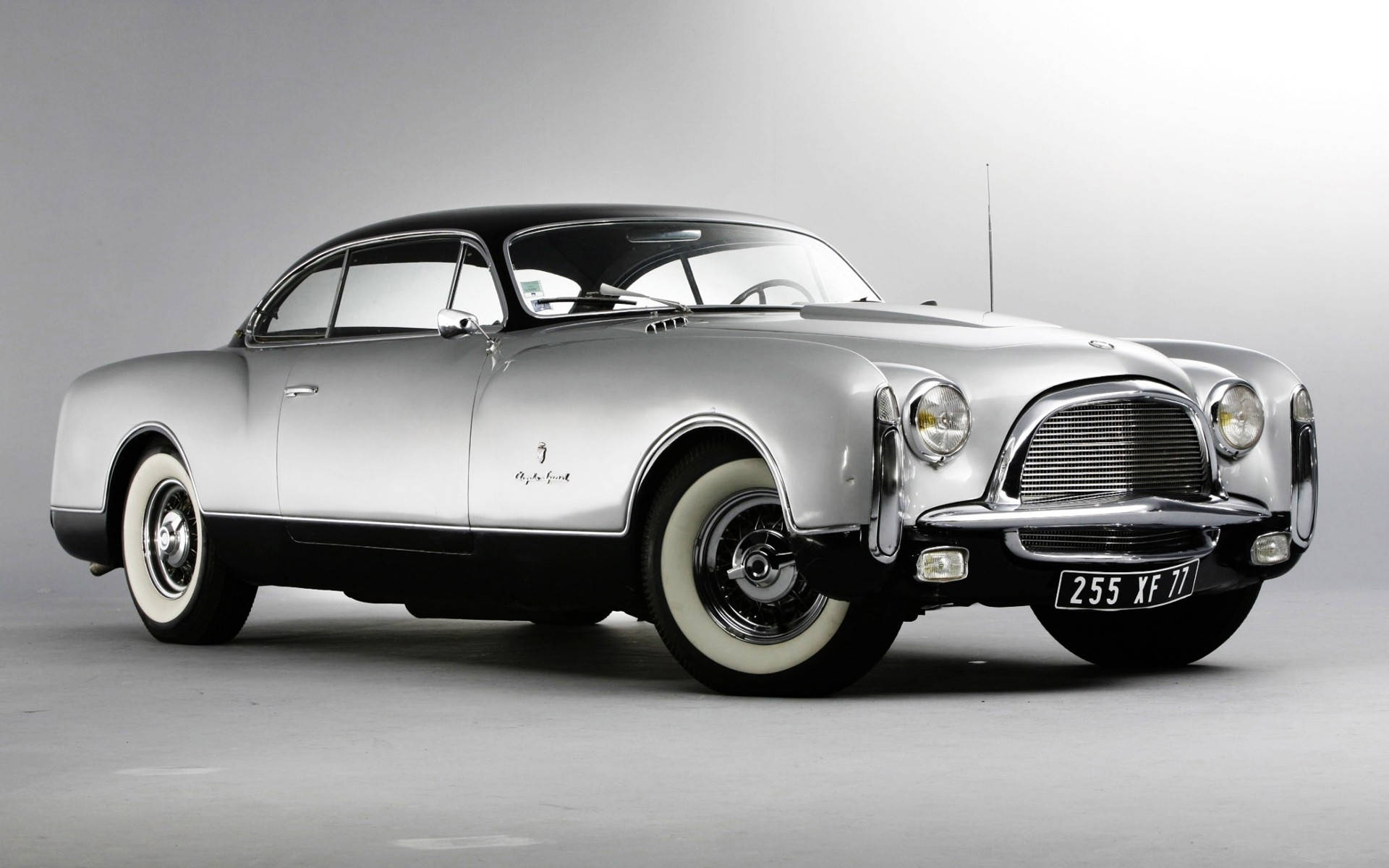 Chrysler 300 豪華版 壁紙 — 一輛時尚的銀色復古愛快羅密歐2500 Coupe，黑色車頂和白色輪胎，在灰色工作室背景前擺拍。
