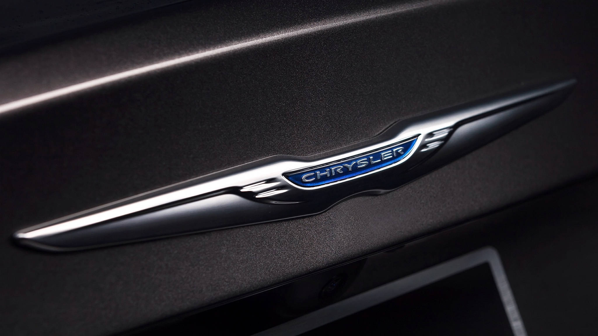 Chrysler 奢華車標誌 壁紙 — 特寫：啞光黑色車內飾板上帶有藍色背光的時尚銀色 Chrysler 標誌。