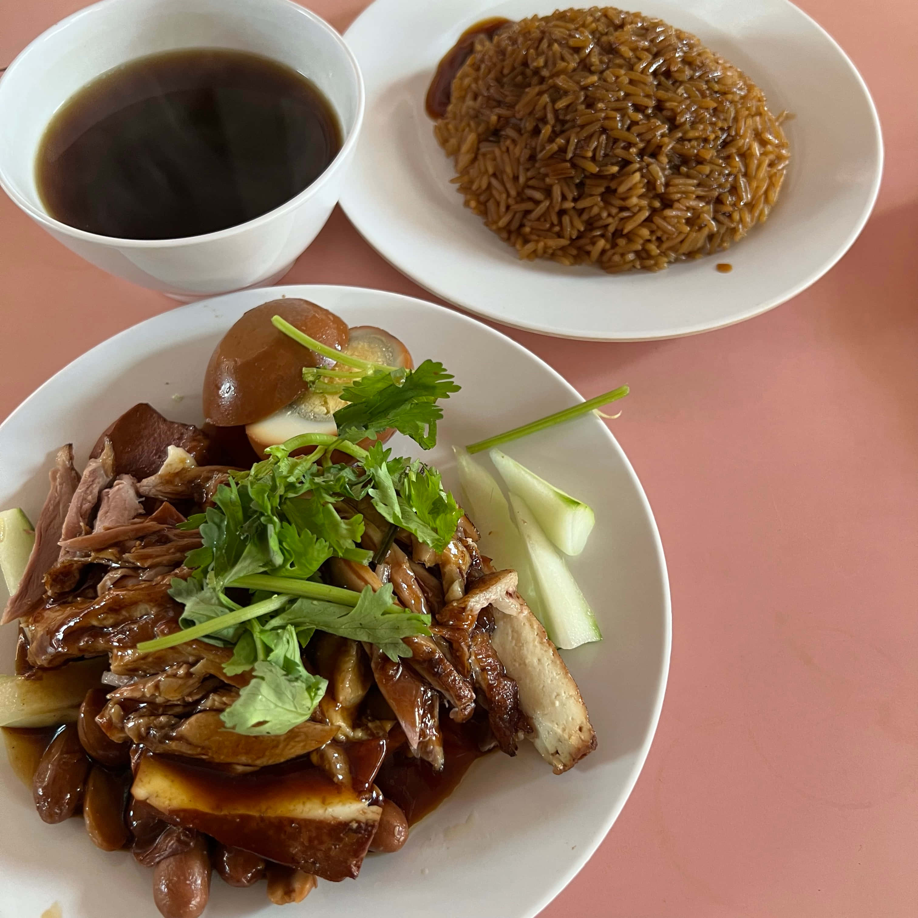 新加坡鴨飯：Chuan Kee 骨無鴨 壁紙 — 粉紅色餐桌上，燉鴨配芫荽青瓜、糙米和深色醬汁的美味菜餚特寫。
