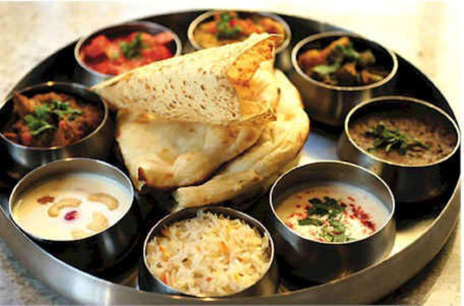 Indian Food 桌布 壁紙 — 傳統印度塔利，配有烤餅和色彩繽紛的咖喱，盛載於金屬碗中，放在圓形托盤上。