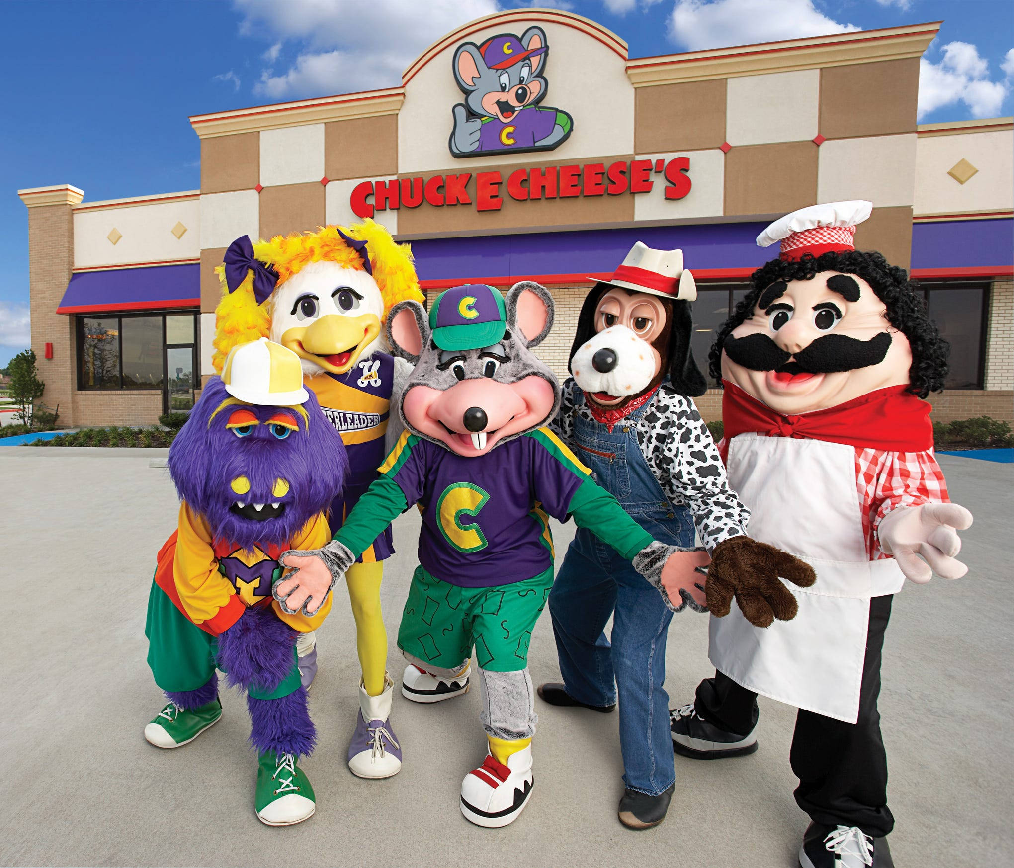 Chuck E Cheese餐廳吉祥物 壁紙 — 五個色彩繽紛的 Chuck E Cheese 吉祥物角色在明亮的藍天下，於他們的主題餐廳前愉快地擺姿勢。