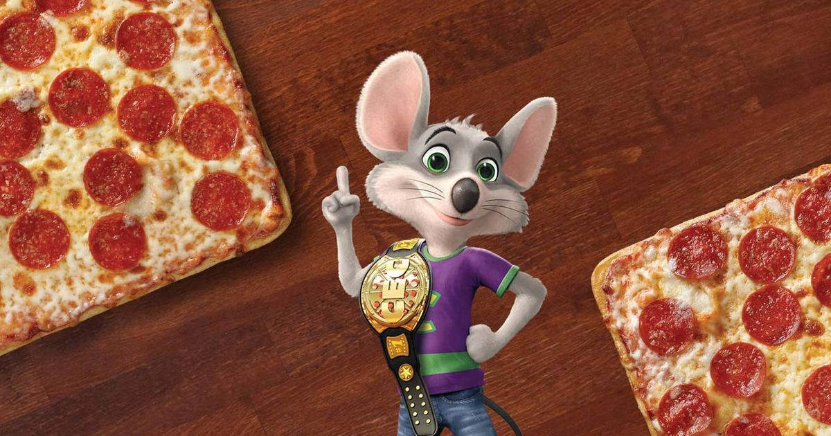 Chuck E Cheese戴冠軍腰帶 壁紙 — 一隻穿著紫色襯衫和冠軍腰帶的卡通老鼠，自豪地站在木桌上兩個意大利辣香腸薄餅之間。
