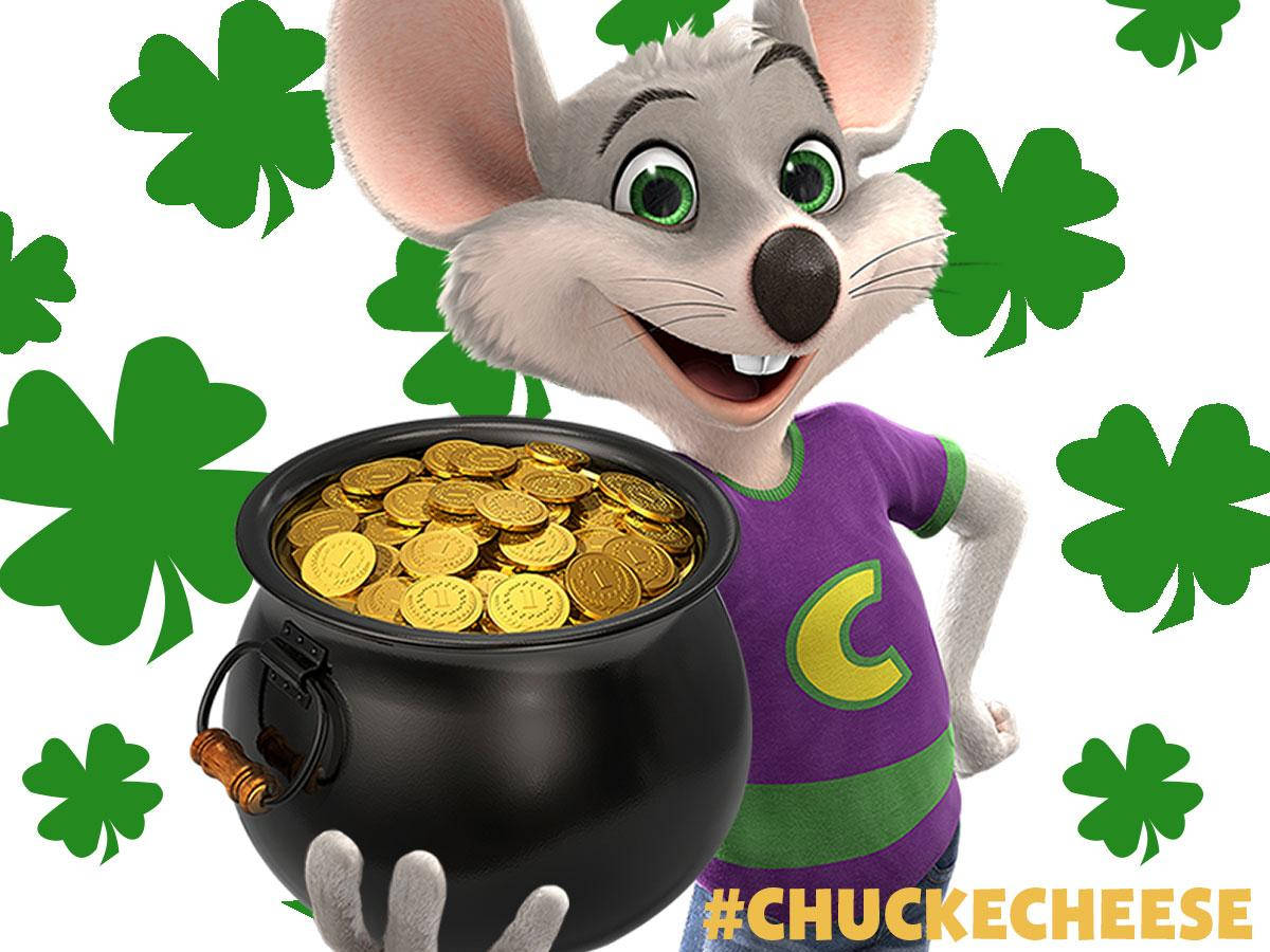 Chuck E Cheese持金幣 壁紙 — 一隻穿著紫色襯衫的開心動畫老鼠，拿著一個裝滿金幣、周圍環繞著綠色三葉草的黑鍋。
