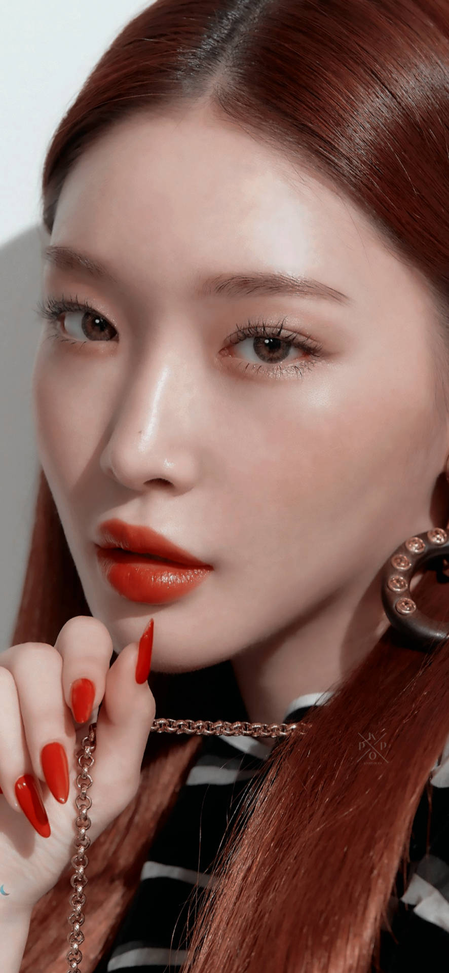 紅髮紅唇的女性在嘴唇附近拿著一條鏈條。