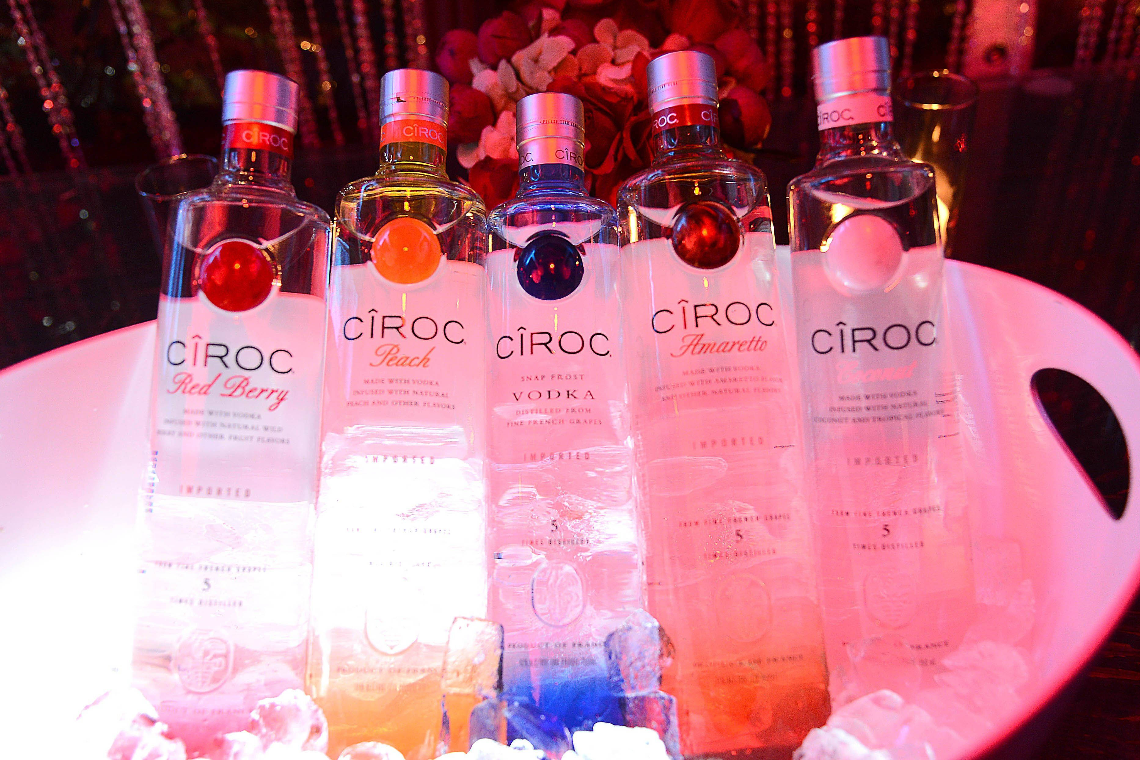 Ciroc 法國伏特加瓶身置於冰桶中 壁紙 — 五瓶不同口味的Cîroc伏特加酒，在閃爍的背景中，放在一個發光的粉紅色碗裡冰鎮。