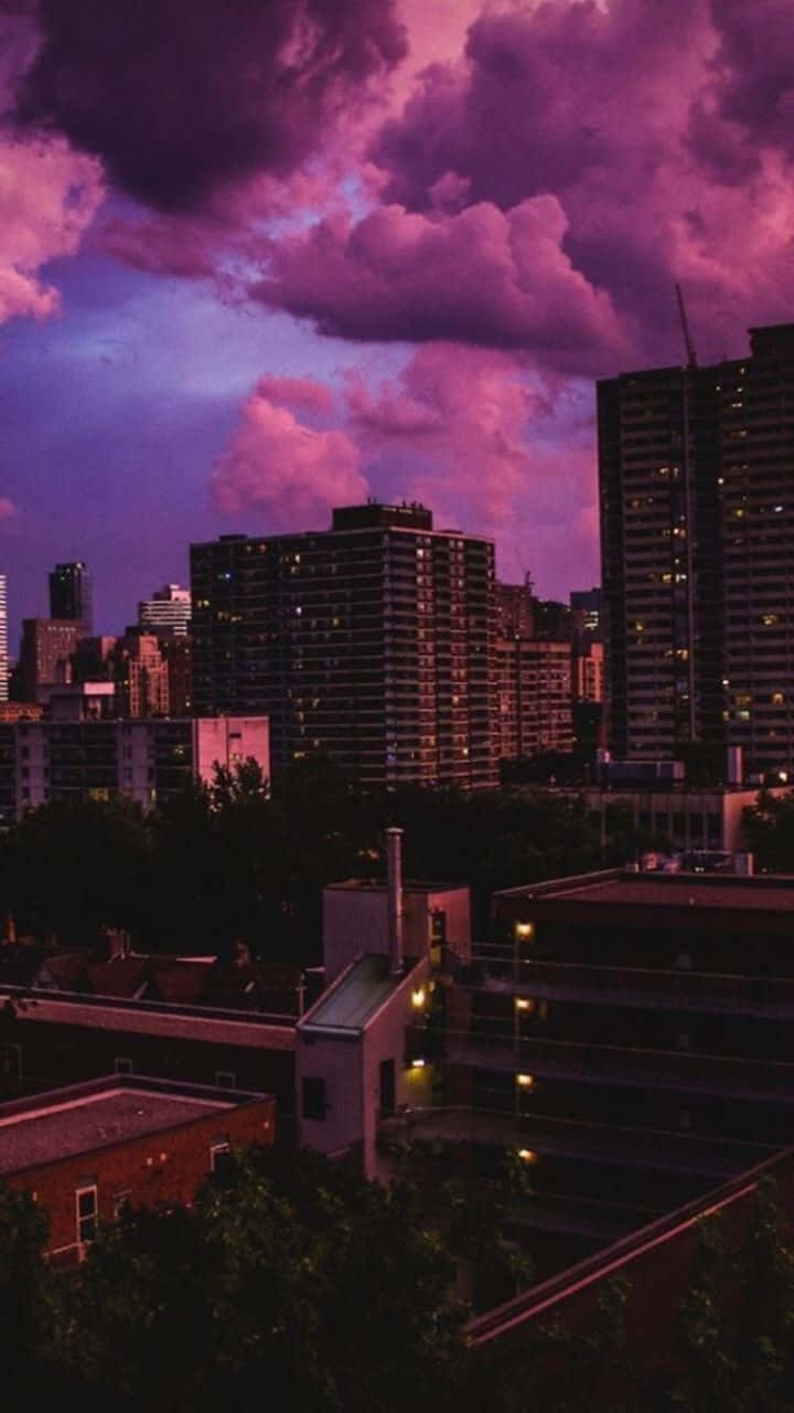  壁紙 — 城市天際線沐浴在暮色紫雲中，亮著的窗戶在漸暗的天空下閃耀。