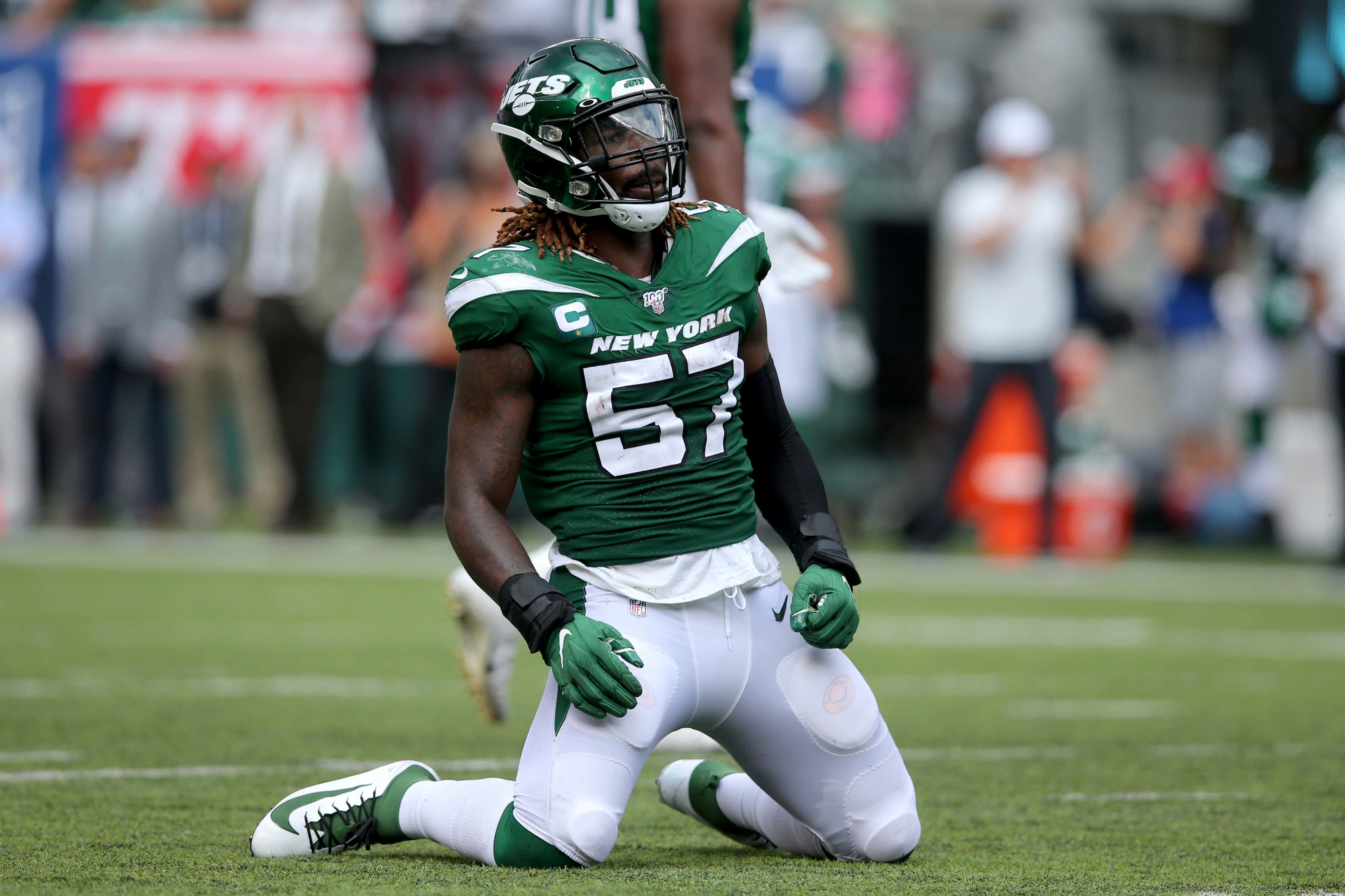 美式足球線衛CJ Mosley 2019 NFL比賽 壁紙 — 一名紐約噴射機美式足球員穿著綠色和白色67號球衣跪在草地上。