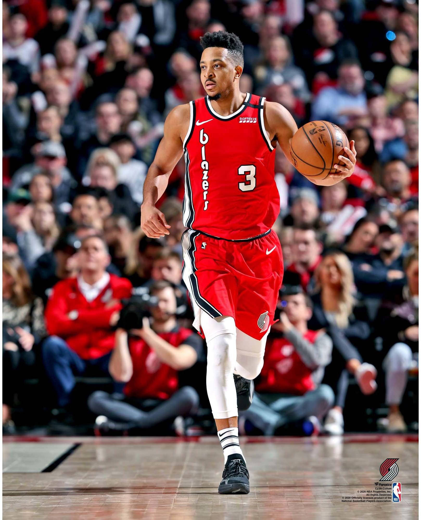 CJ麥可盧姆賽場運球特寫 壁紙 — 一名身穿紅色 Blazers 球衣的籃球運動員在比賽中運球，背景是人群。