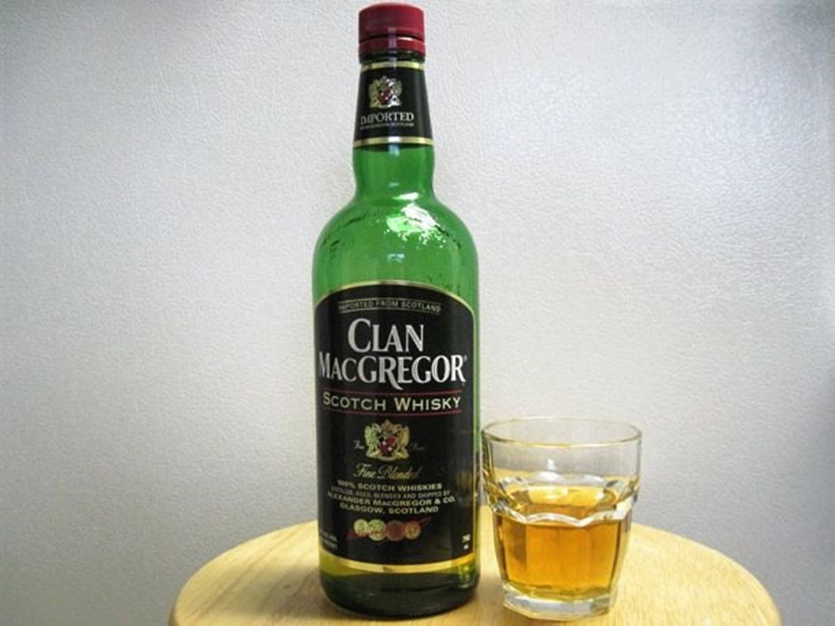 綠色威士忌酒瓶同木枱上嘅琥珀色液體玻璃杯。