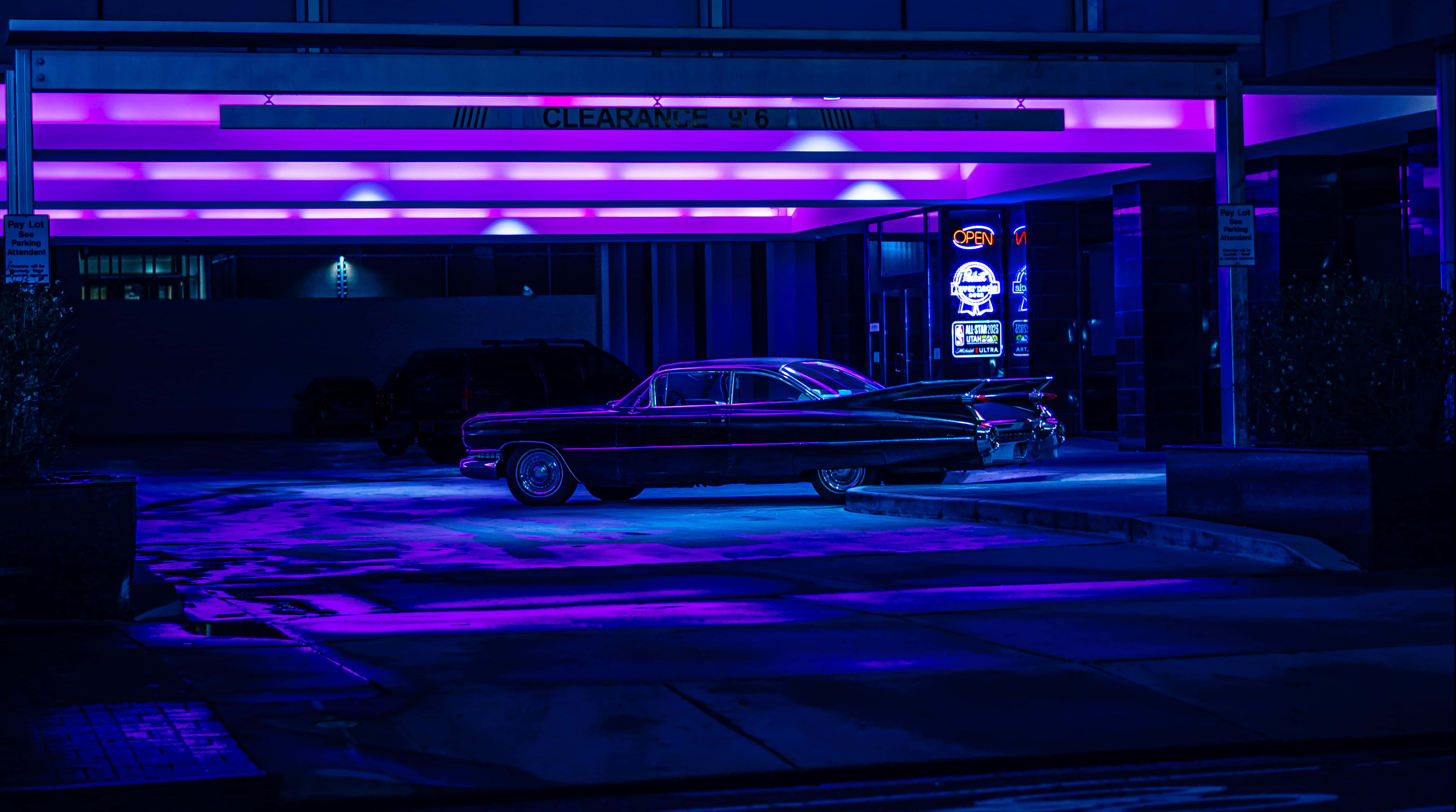 Cadillac Deville 桌布 壁紙 — 一輛經典汽車在夜晚的復古汽車旅館外，在充滿活力的紫色霓虹燈下閃閃發光。