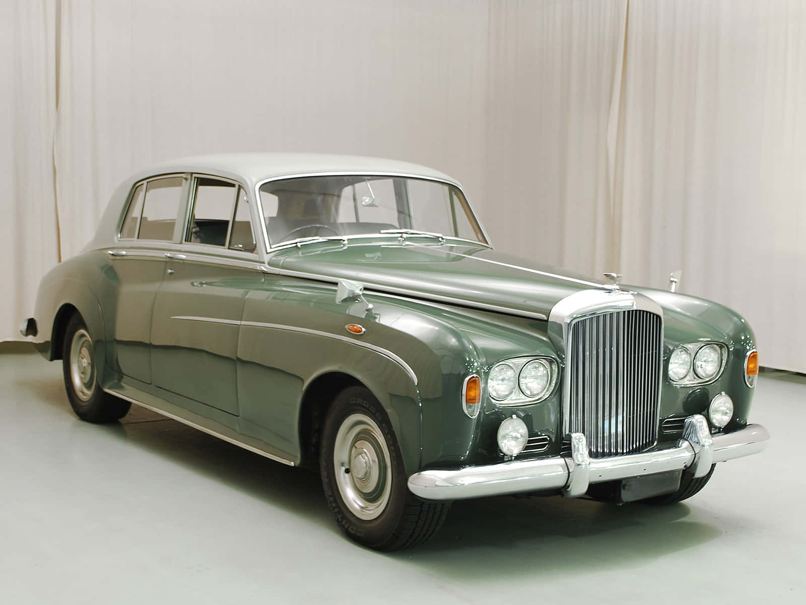 Bentley S3 桌布 壁紙 — 經典綠色賓利轎車，帶有鍍鉻裝飾和白色輪胎，在明亮的攝影棚中展示。
