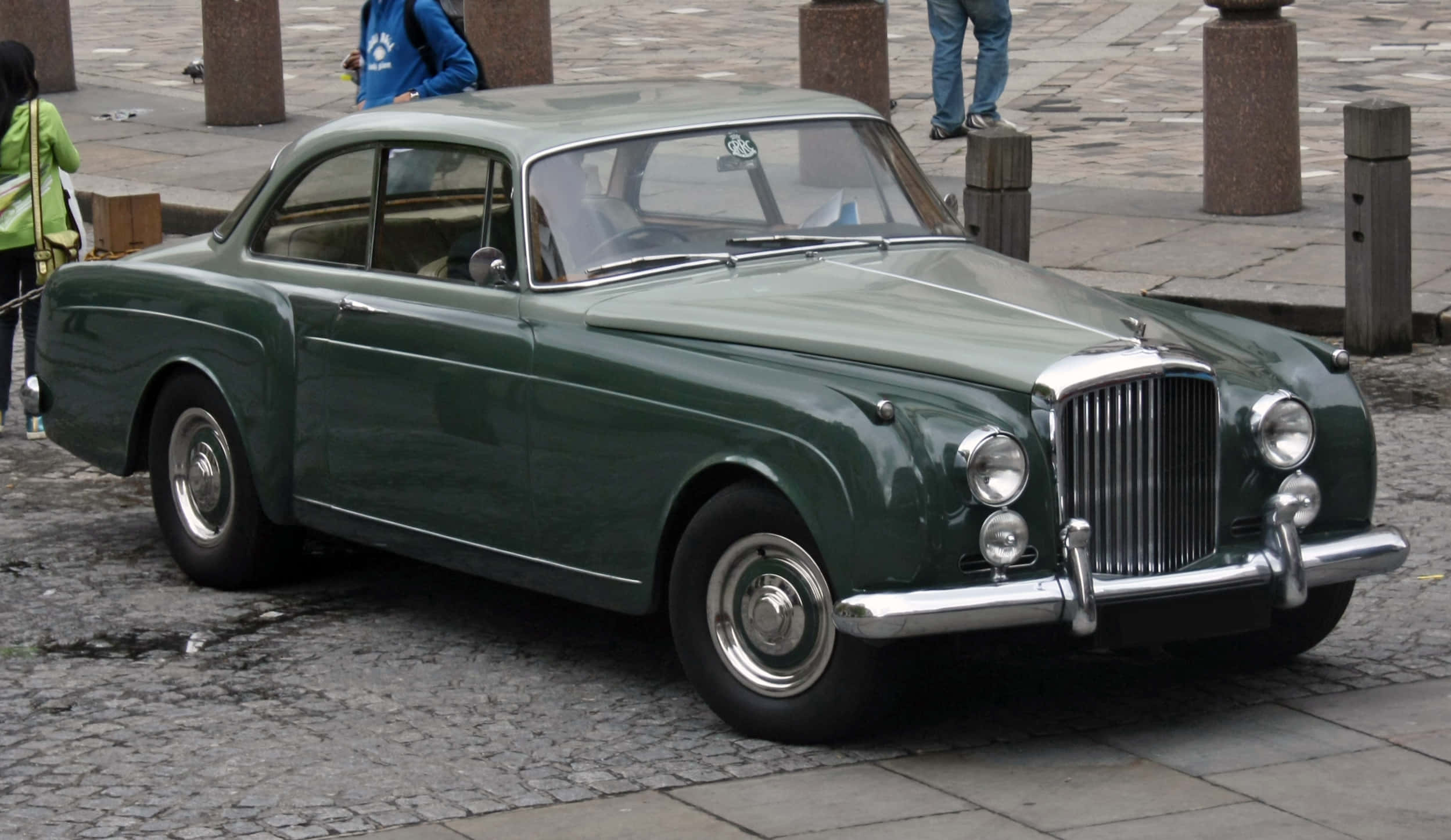 Bentley S2 桌布 壁紙 — 一輛經典綠色賓利轎車停泊在濕漉漉的鵝卵石街道上，附近有行人。