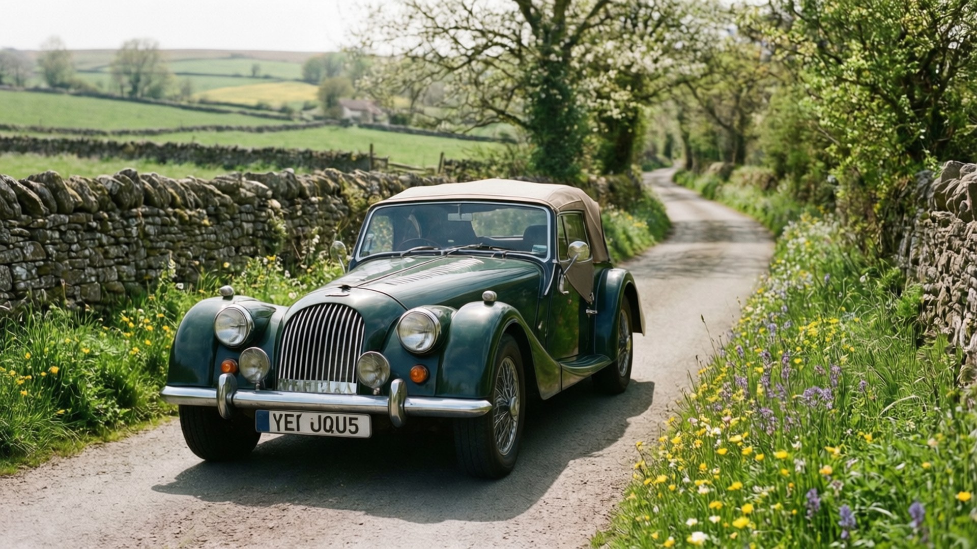 Morgan Plus Six 桌布 壁紙 — 一輛經典綠色摩根開篷跑車在明媚日光下行駛於蜿蜒的鄉村小徑，小徑兩旁是石牆和野花。